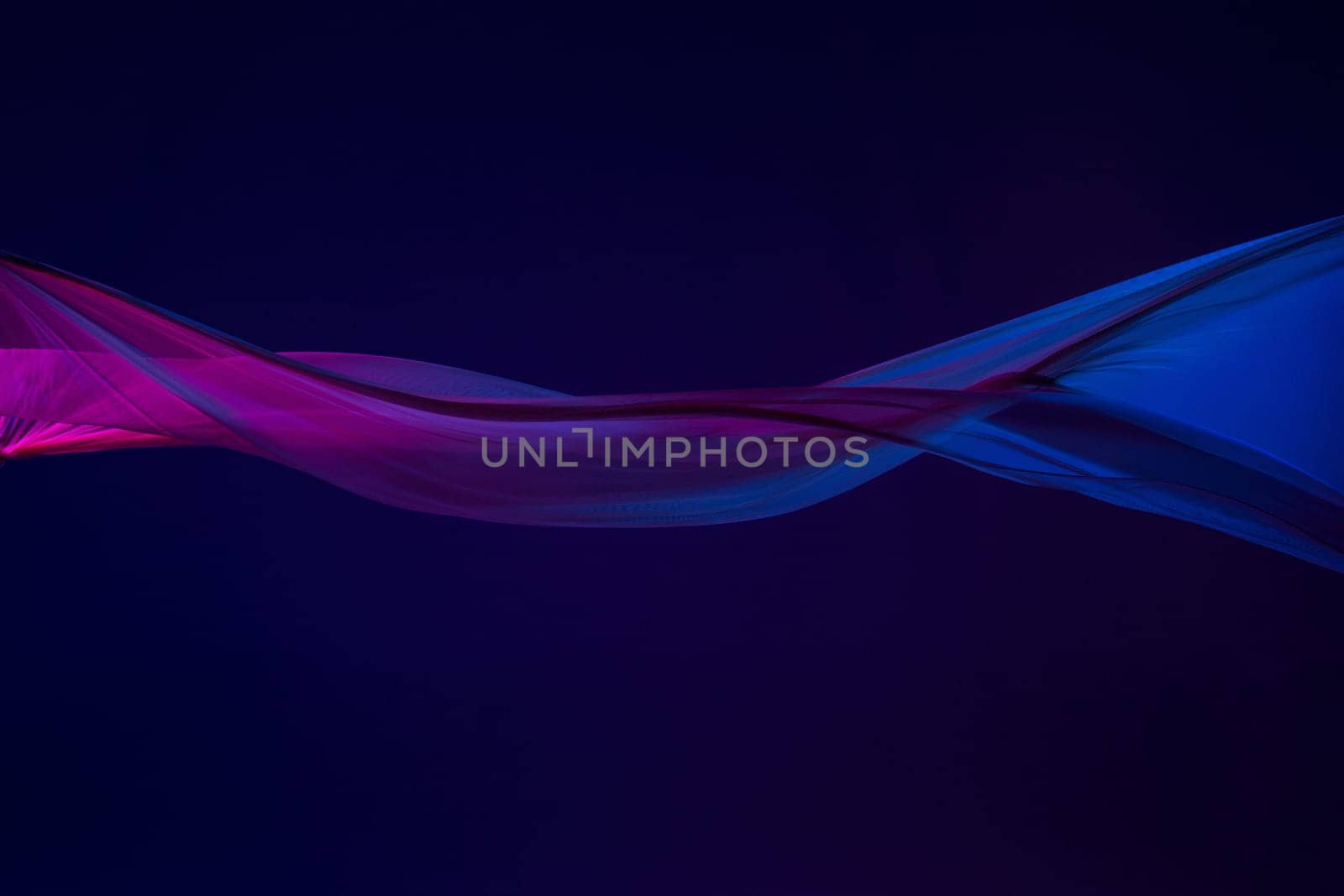 Smooth elegant transparent blue cloth isolated or separated on dark blue studio background. Texture of flying silk fabric.