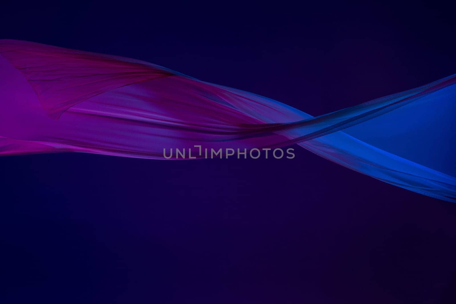 Smooth elegant transparent blue cloth isolated or separated on dark blue studio background. Texture of flying silk fabric.