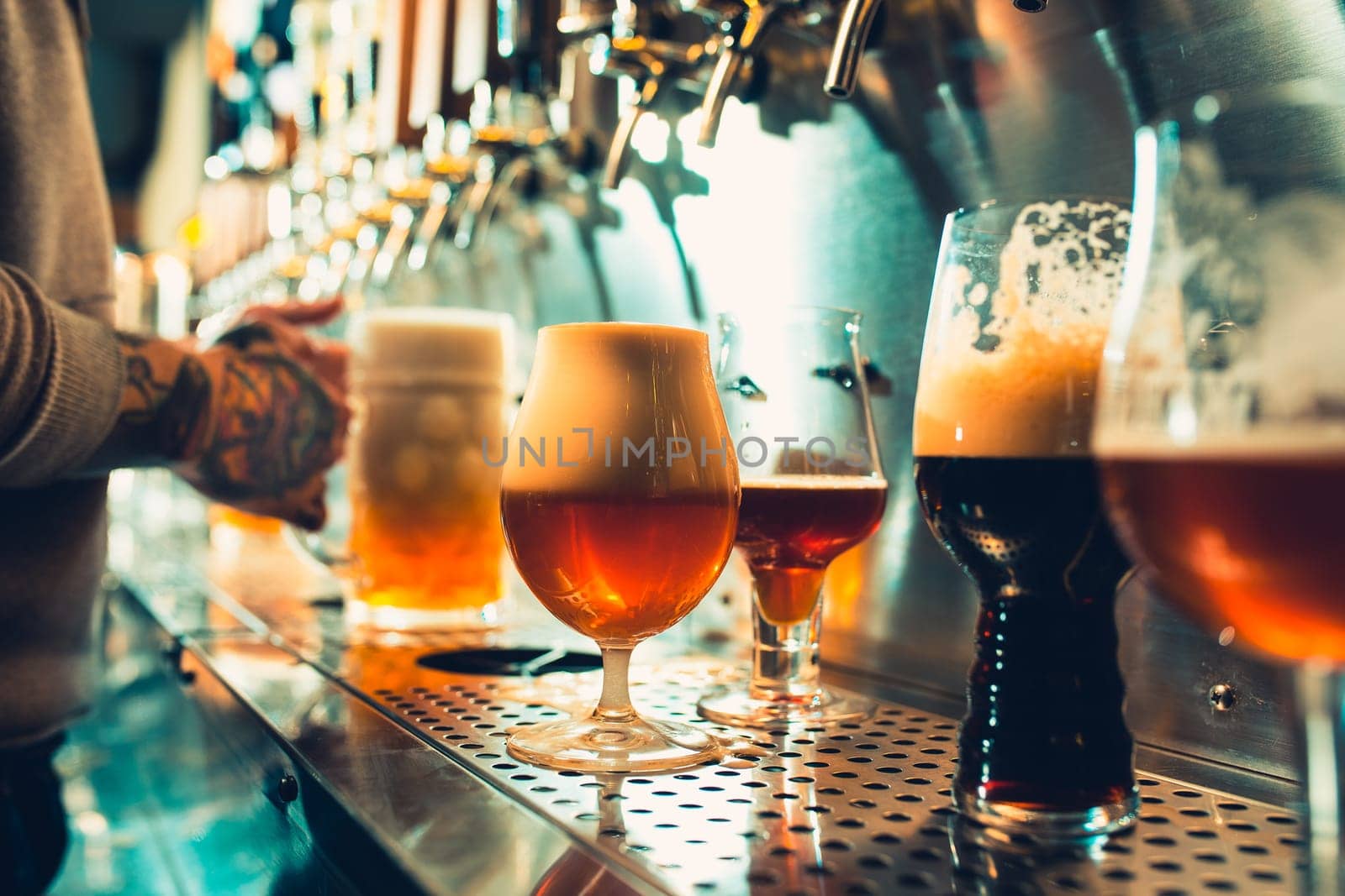 We meet oktoberfest. Hand of bartender pouring a large lager beer in tap. Pouring beer for client. Side view of young bartender pouring beer while standing at the bar counter