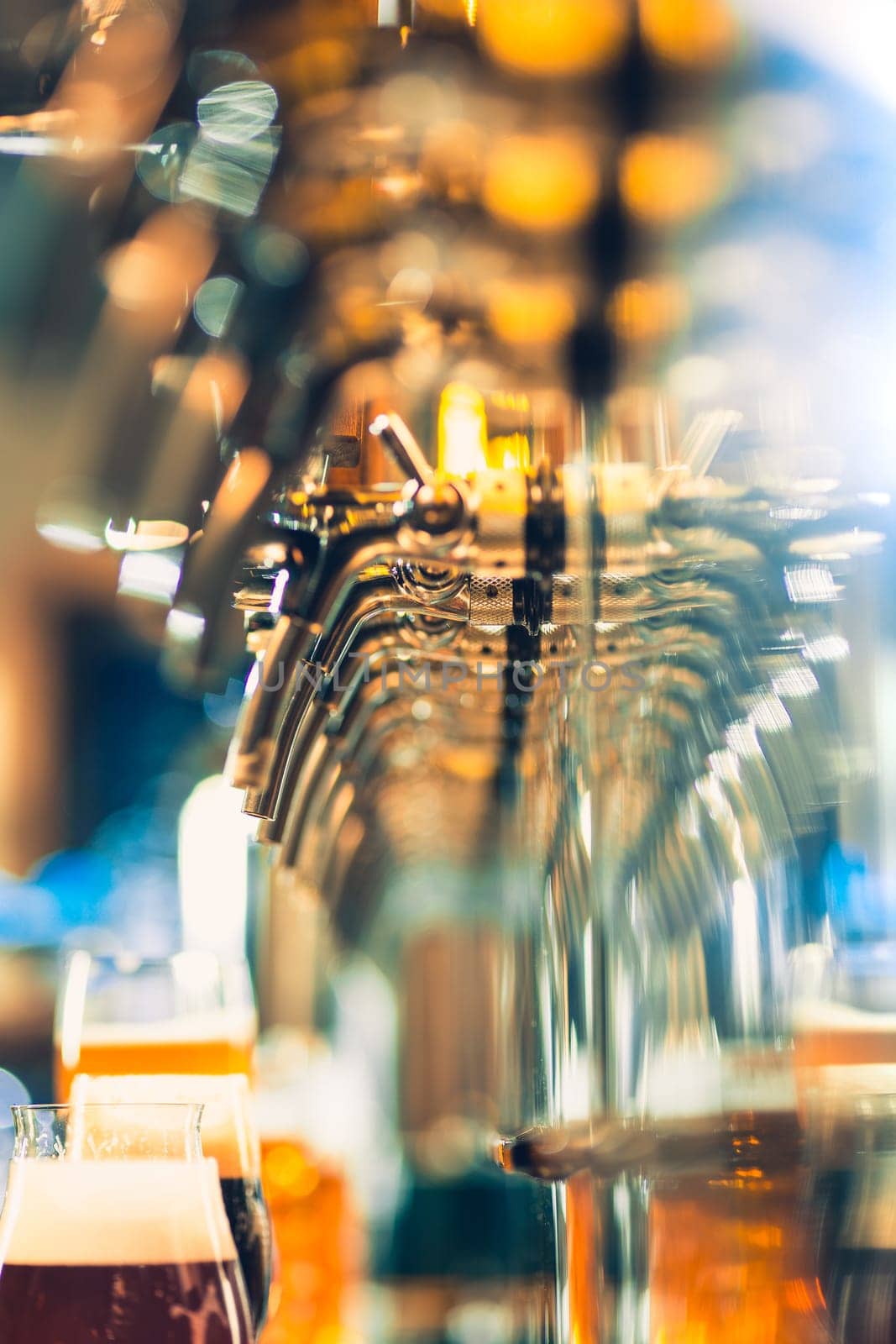 The beer taps in a pub. nobody. Selective focus. Alcohol concept. Vintage style. Beer craft. Bar table. Steel taps. Shiny taps. Glass of beer