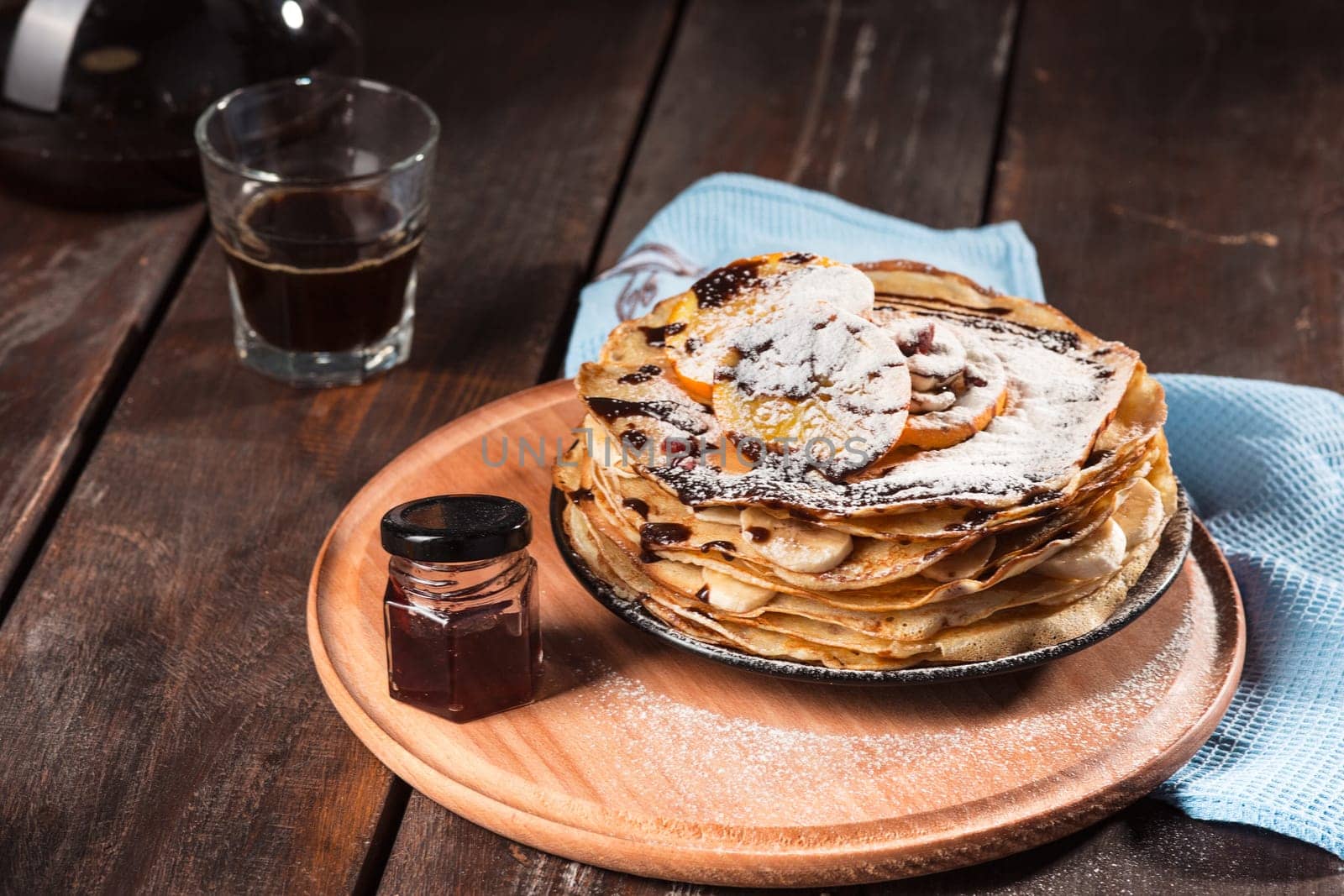 Fresh homemade french crepes made with ffresh fruits on a vintage wooden board on the wooden table. Side view with honey, fruits and coffee. French pancakes concept