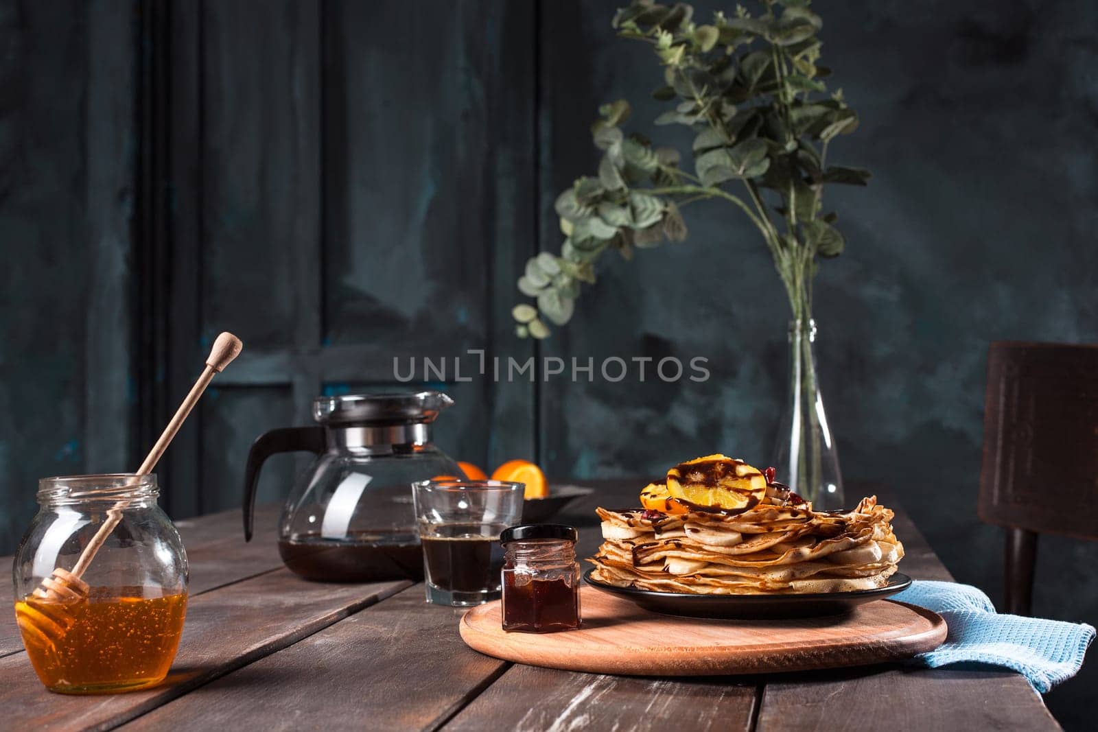 Fresh homemade french crepes made with ffresh fruits on a vintage wooden board on the wooden table. Side view with honey, fruits and coffee. French pancakes concept