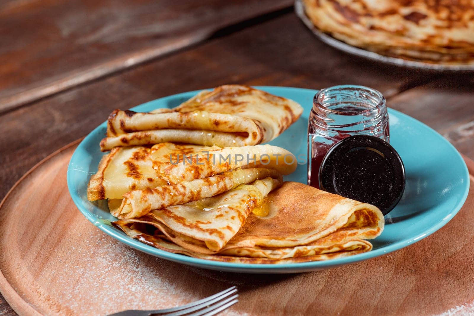 Fresh homemade french crepes made with ffresh fruits on a vintage wooden board on the wooden table. Side view with honey, fruits and coffee. French pancakes concept