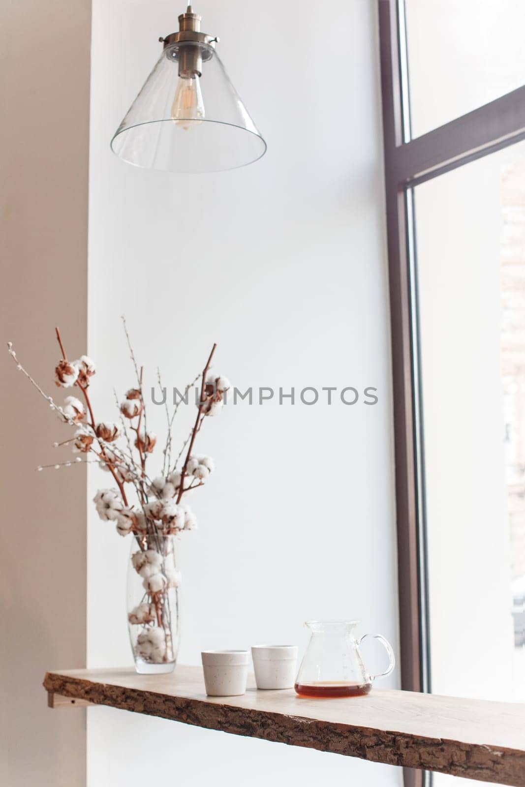 Cup of coffee, branch of tree, wooden windowsill. In the background white window.