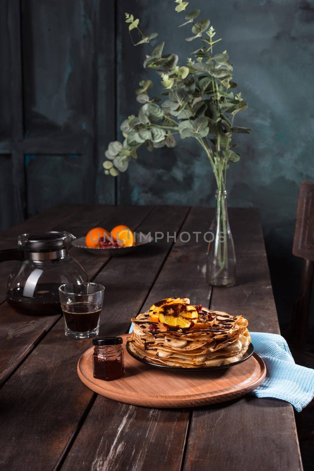 Fresh homemade french crepes made with ffresh fruits on a vintage wooden board on the wooden table. Side view with honey, fruits and coffee. French pancakes concept