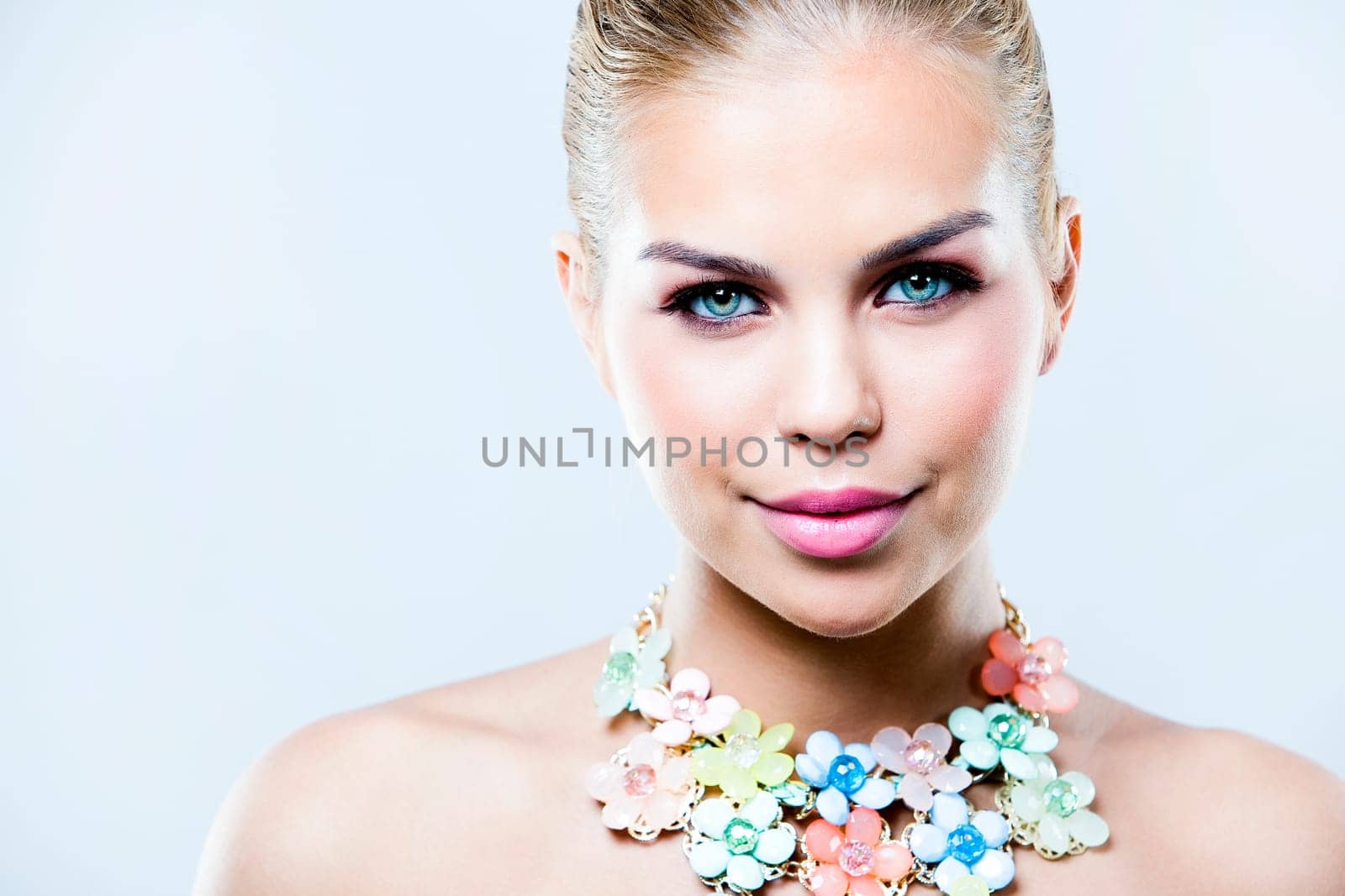 beautiful woman with dark makeup and pink lipstick posing on light background wearing flower spring and summer jewellry necklace