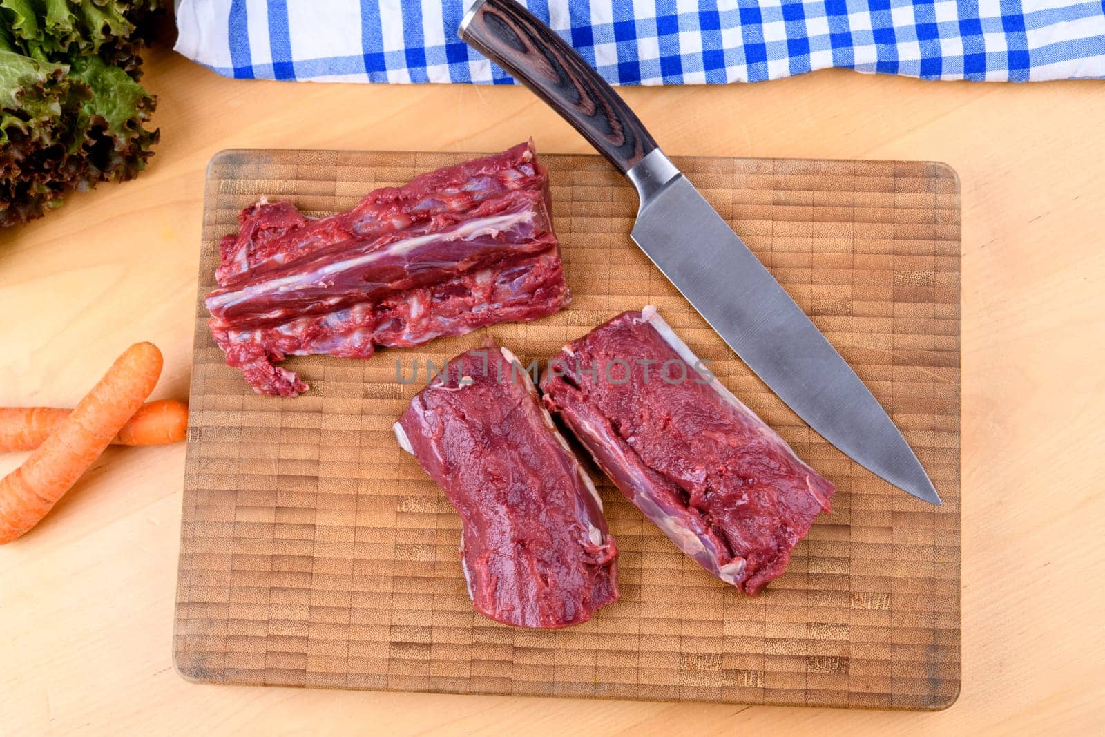 saddle of venison on wooden board with big knife
