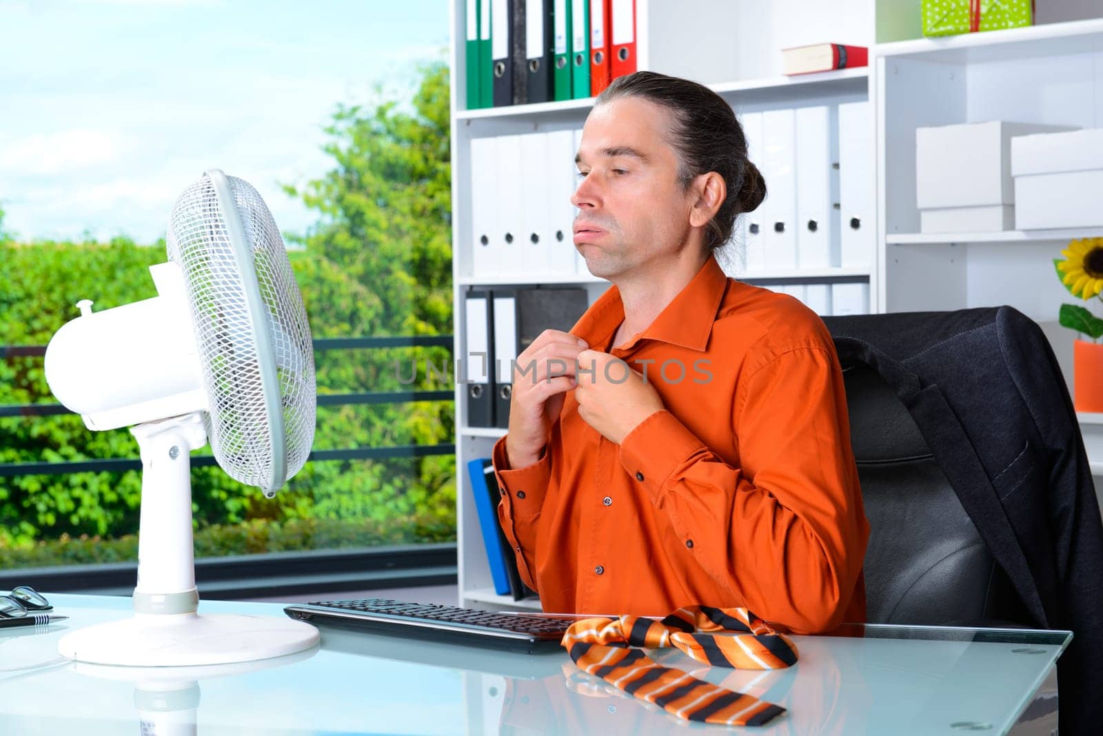 business man with ventilator at his desk in summerly hot office