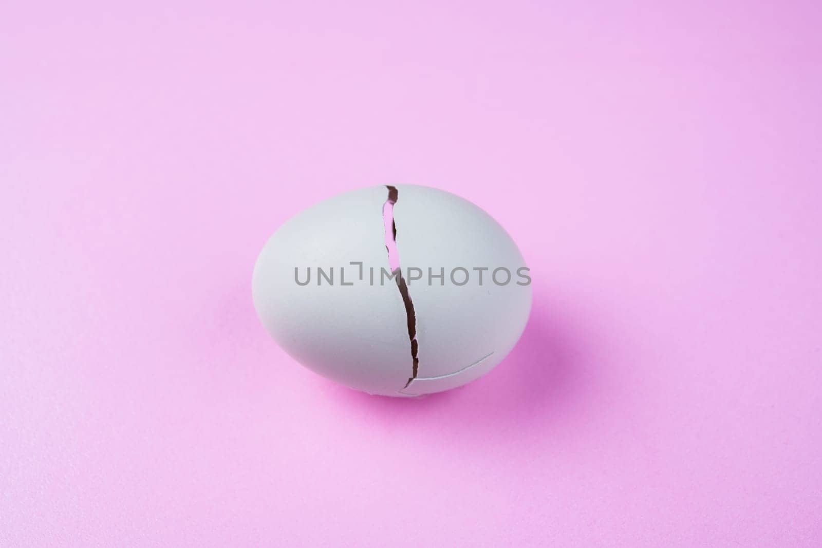 broken egg with crack on pink ground