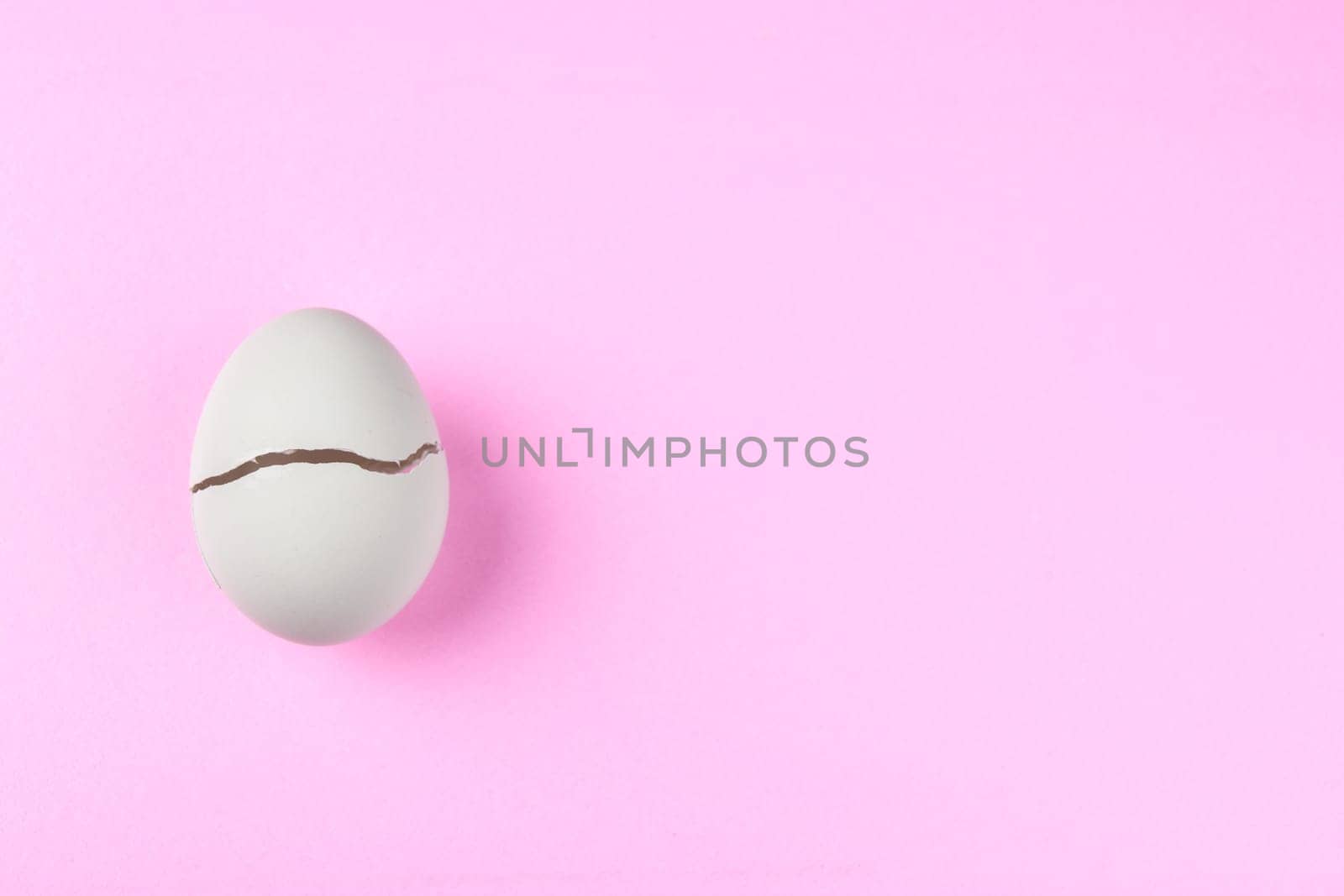 broken egg with crack on pink ground