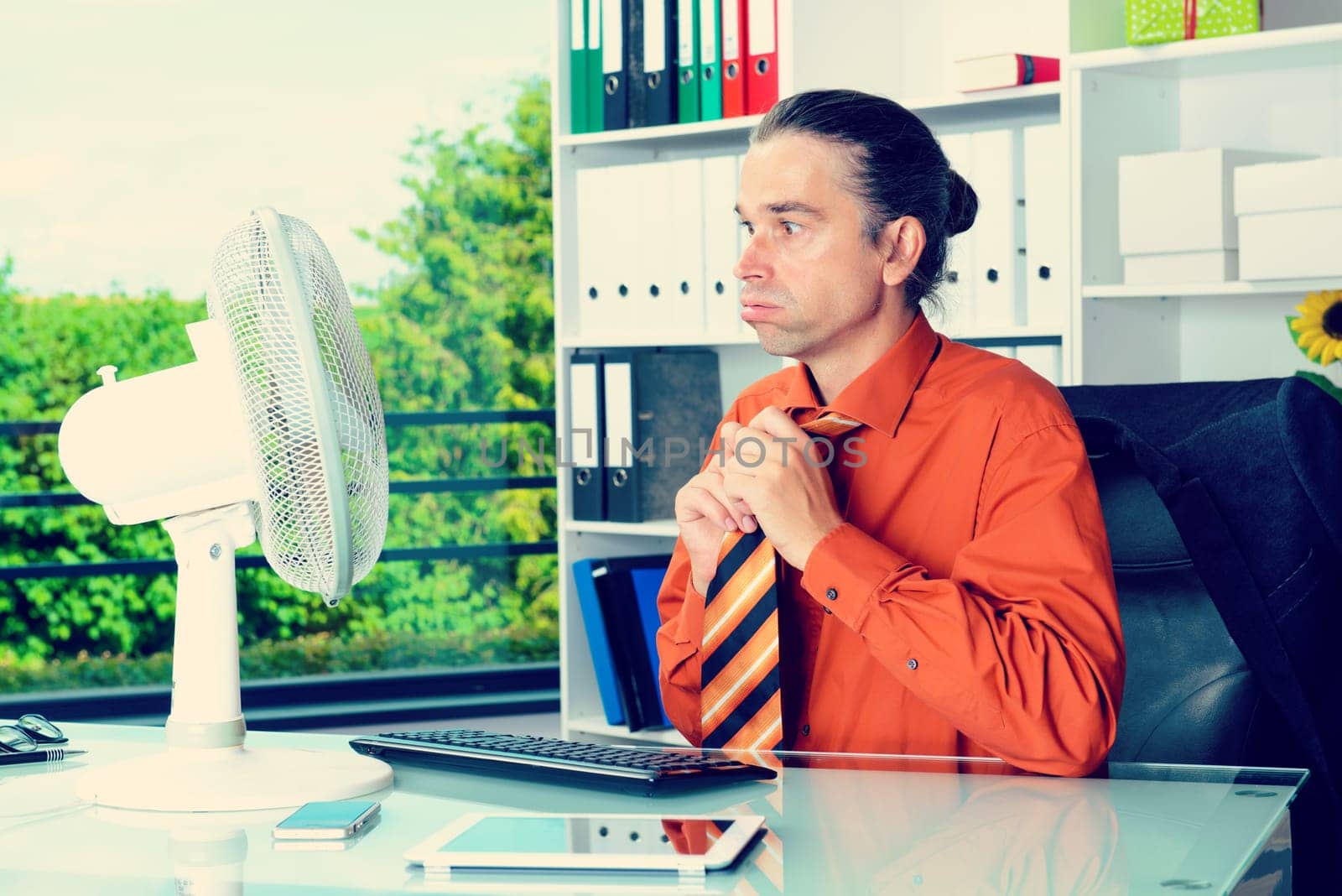 business man with ventilator at his desk in summerly hot office