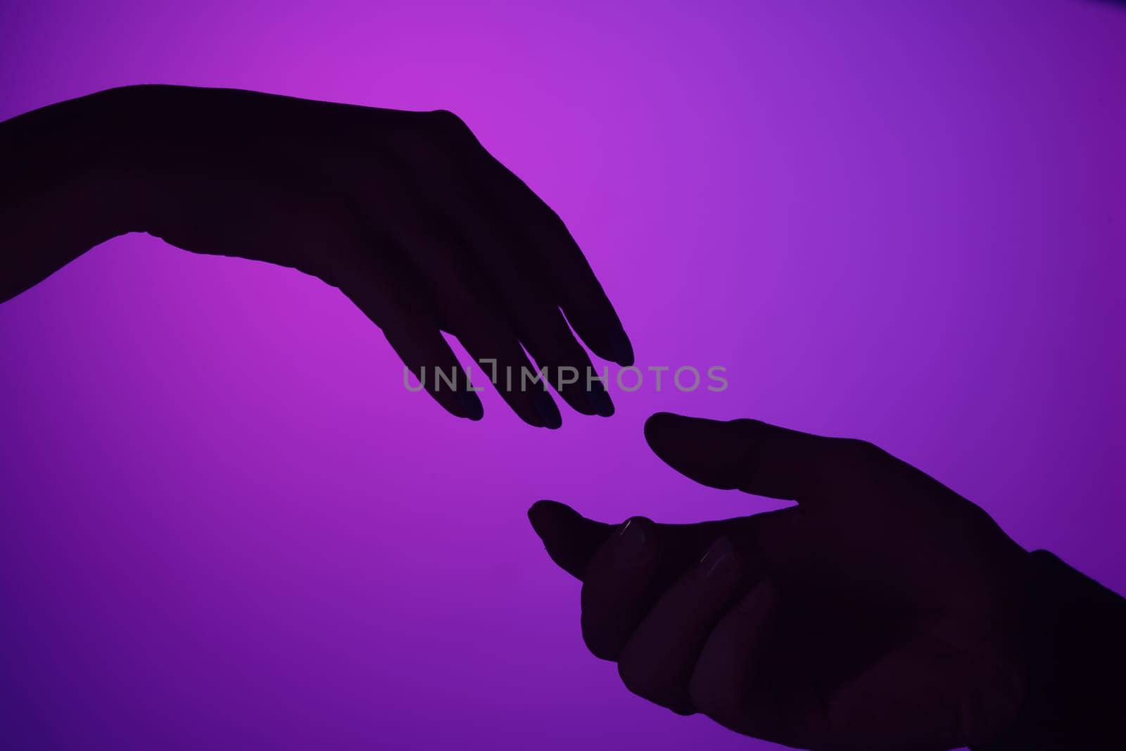 Male and female hands are drawn to each other. concept of care, support, love. Shot at studio. Vivid bright colored lighting. Trendy in 2018 Ultra Violet Light Bulb. Art decoration with tone of mystic color