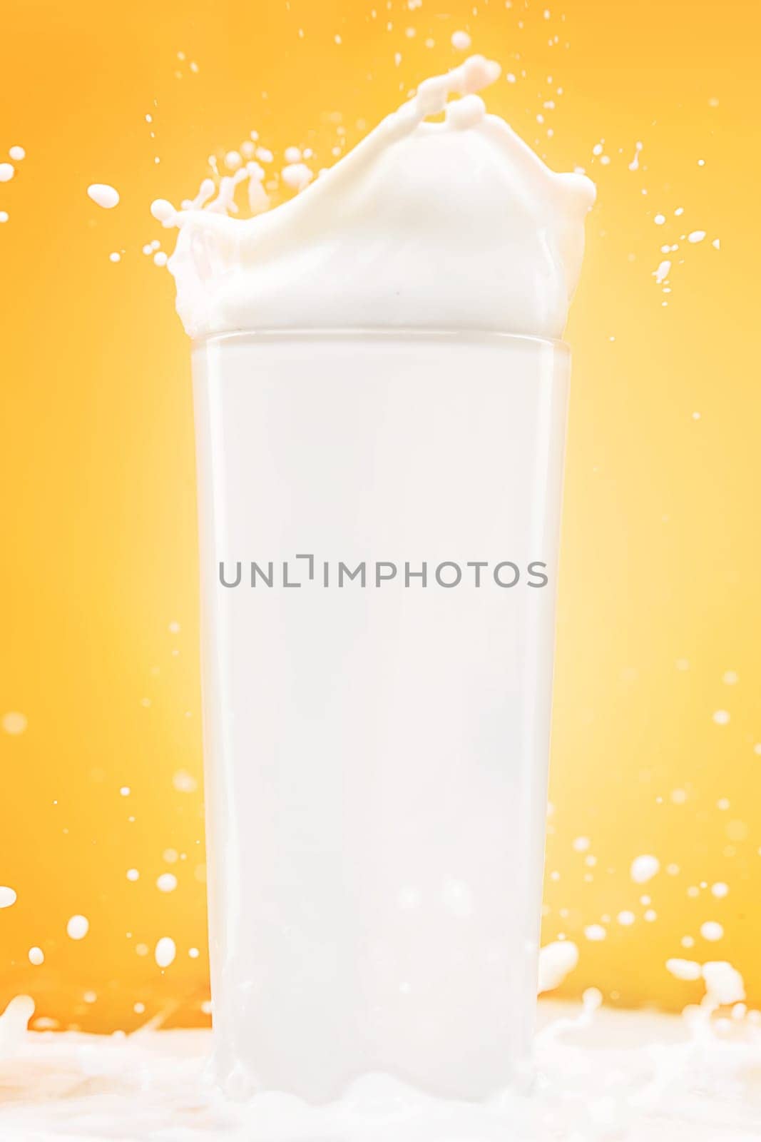 The glass of milk on yellow studio