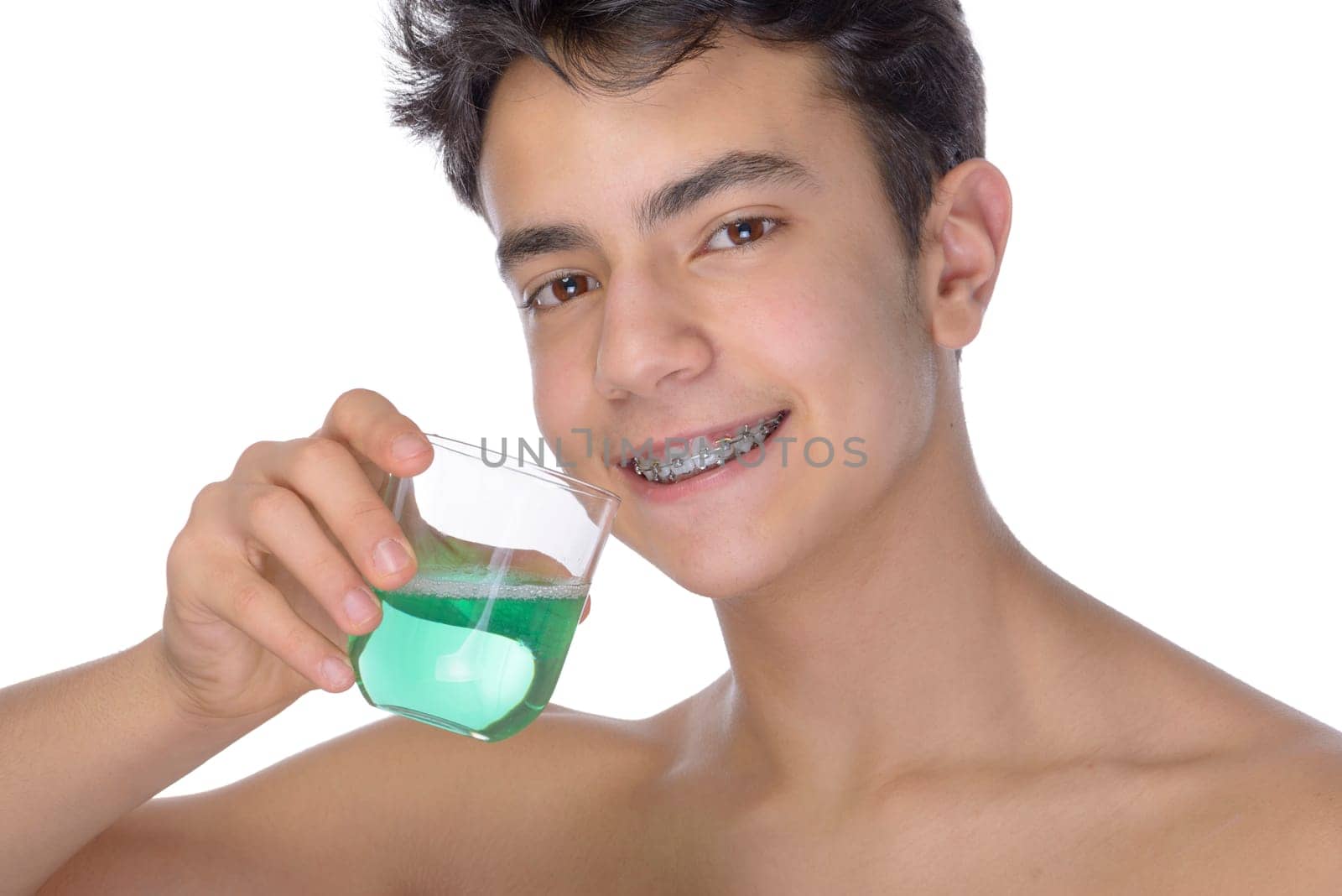 Cute teenager with white background, wearing braces on his teeth. Use mouthwash for oral hygiene.