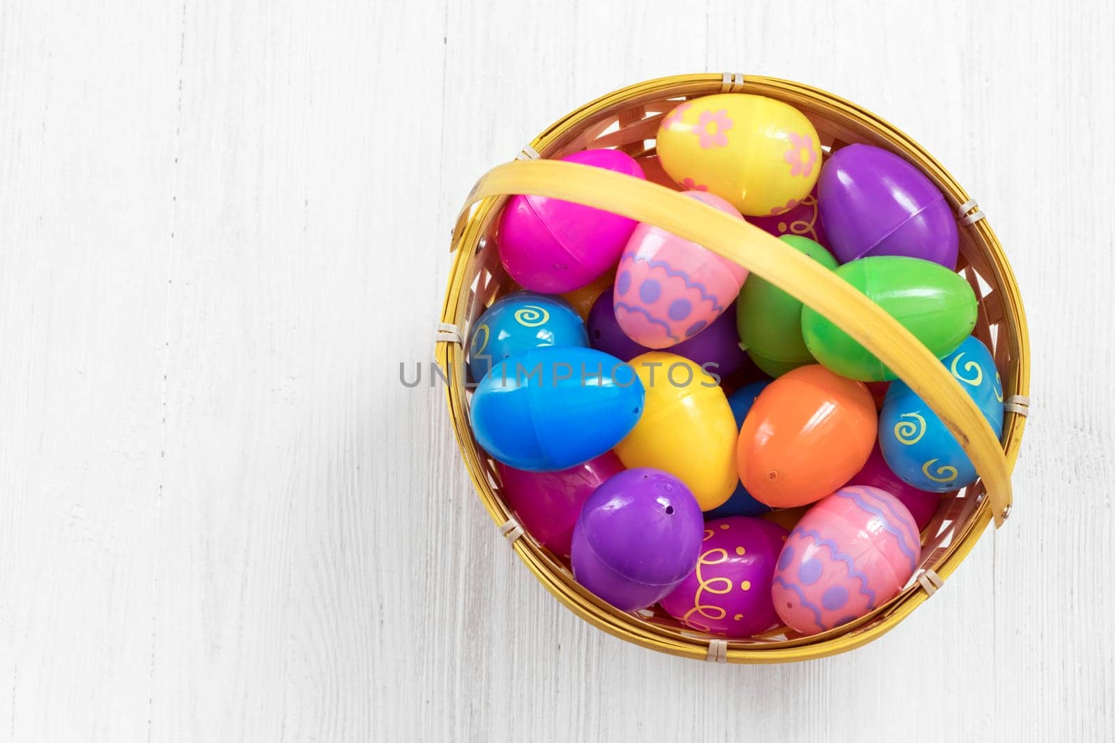 Easter eggs in basket on white wooden background