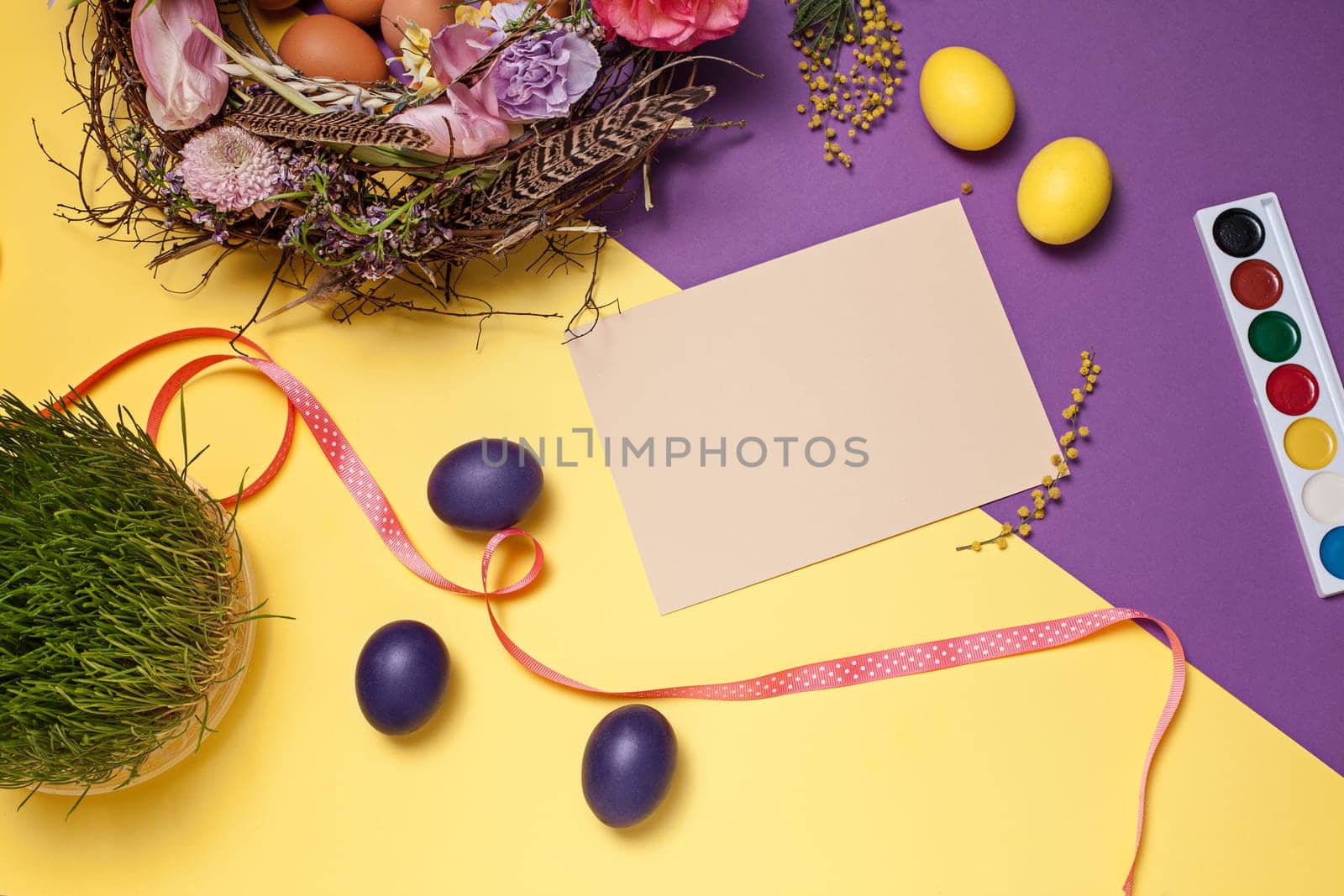 Easter card. Painted Easter eggs in nest on yellow table background. Top view of easter decoration. Happy easter concept. Trendy colors