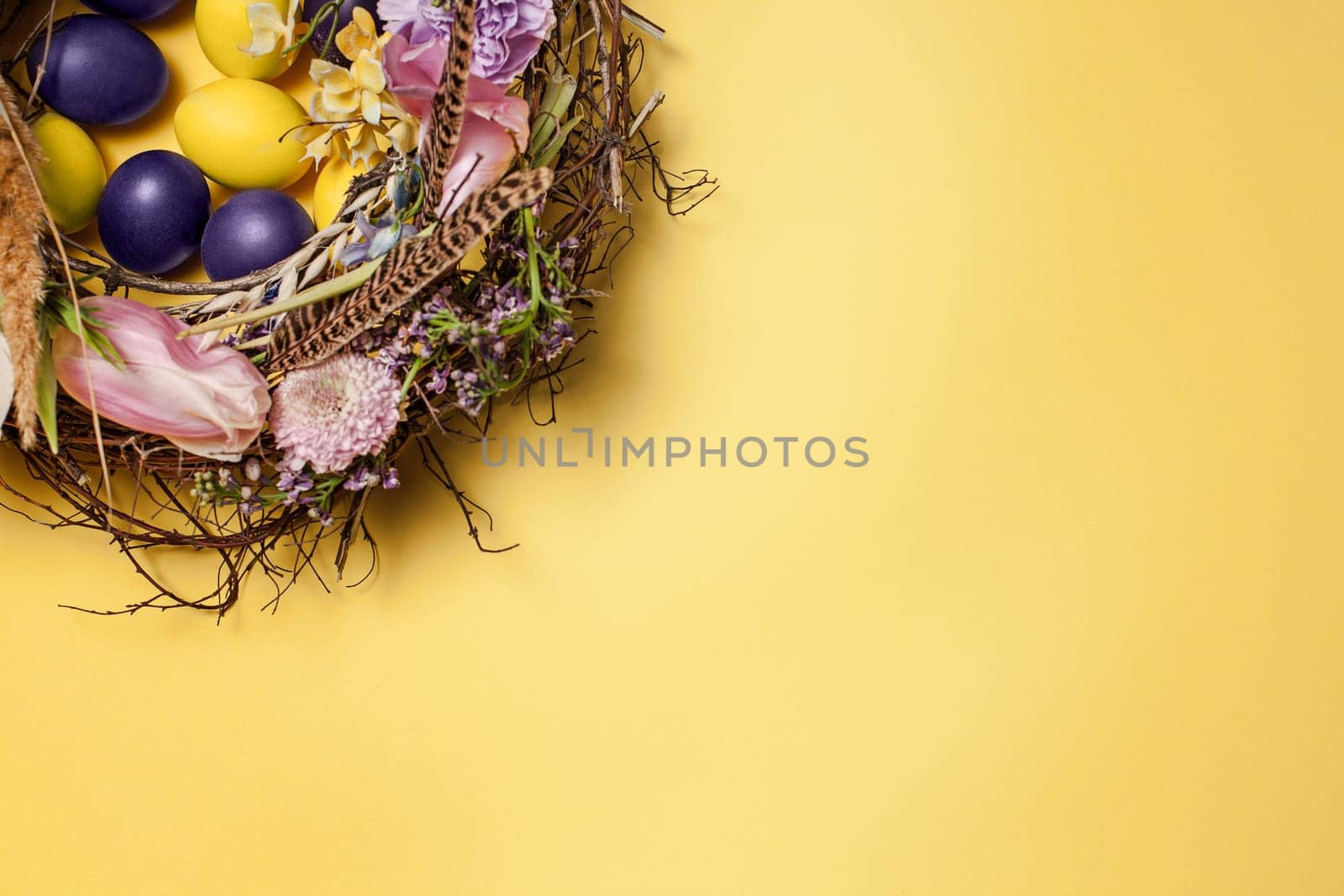 Easter card. Painted Easter eggs in nest on yellow table background. Top view of easter decoration. Happy easter concept. Trendy colors