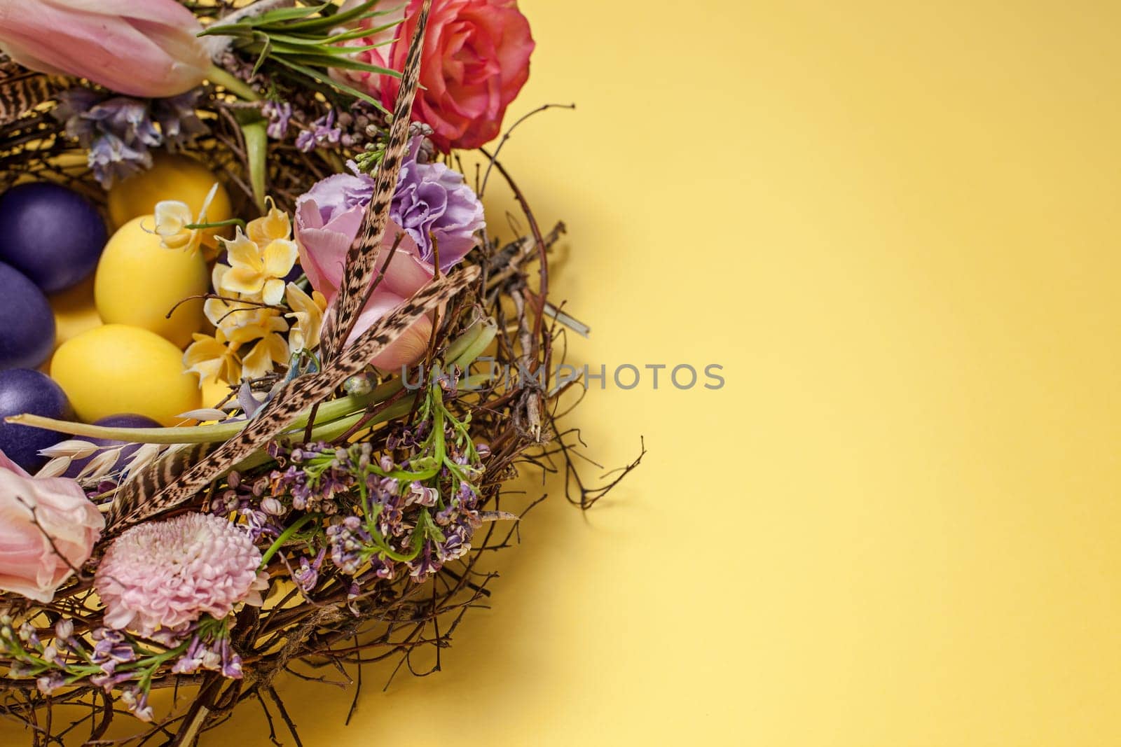Easter card. Painted Easter eggs in nest on yellow table background. Top view of easter decoration. Happy easter concept