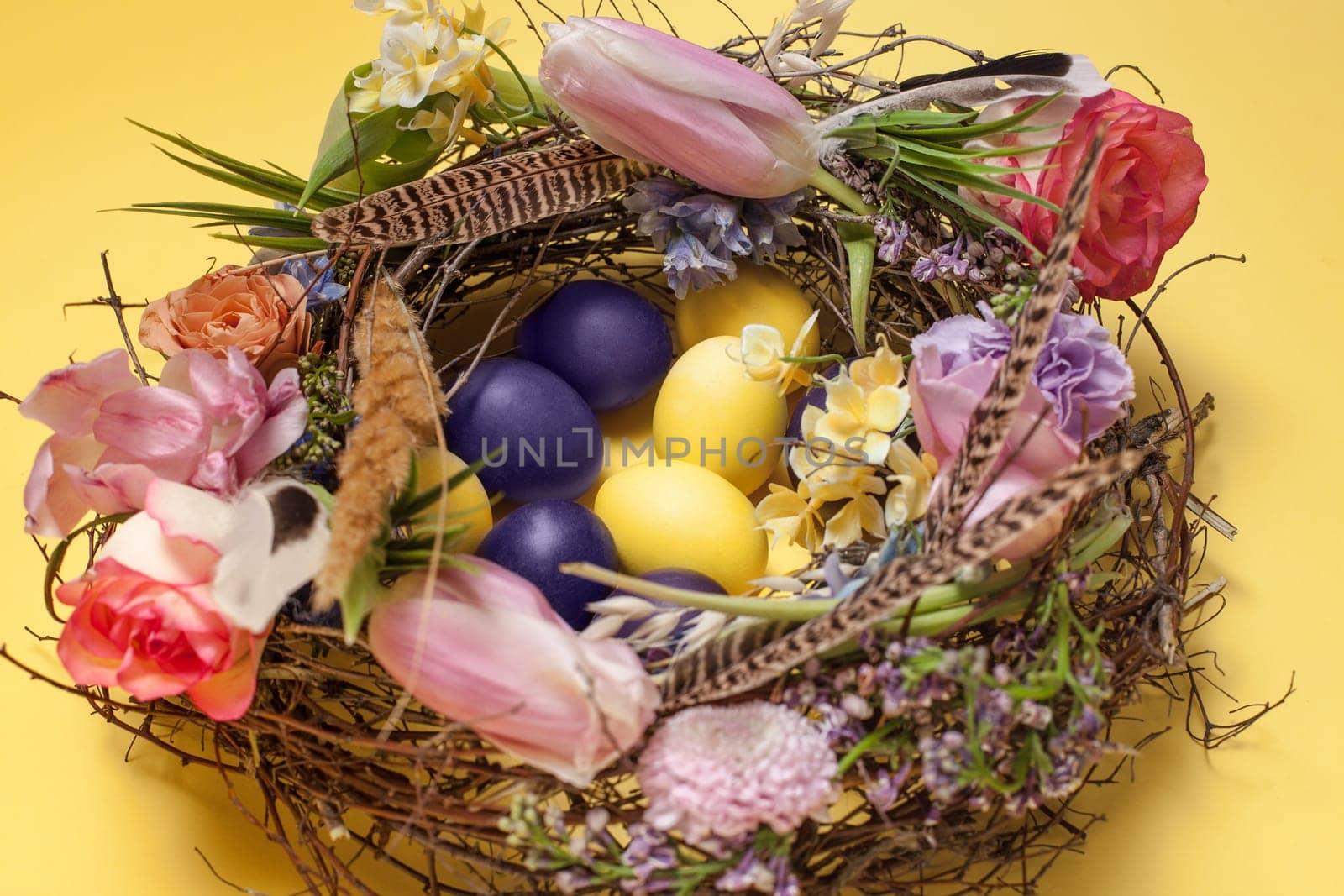 Easter card. Painted Easter eggs in nest on yellow table background. Side view of easter decoration. Happy easter concept