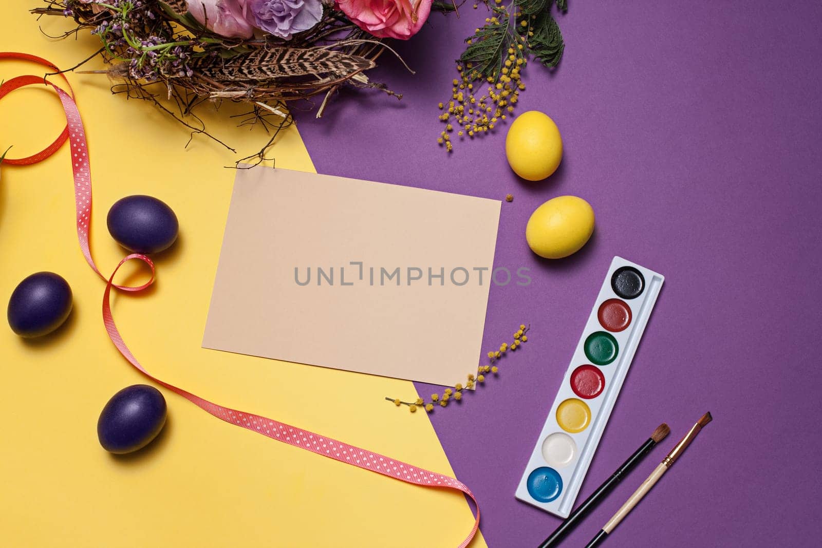 Easter card. Painted Easter eggs in nest on yellow table background. Top view of easter decoration. Happy easter concept. Trendy colors