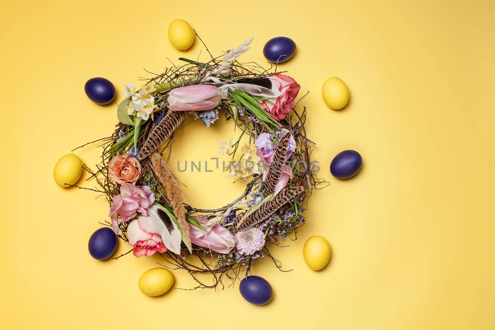 Easter card. Painted Easter eggs in nest on yellow table background. Top view of easter decoration. Happy easter concept. Trendy colors