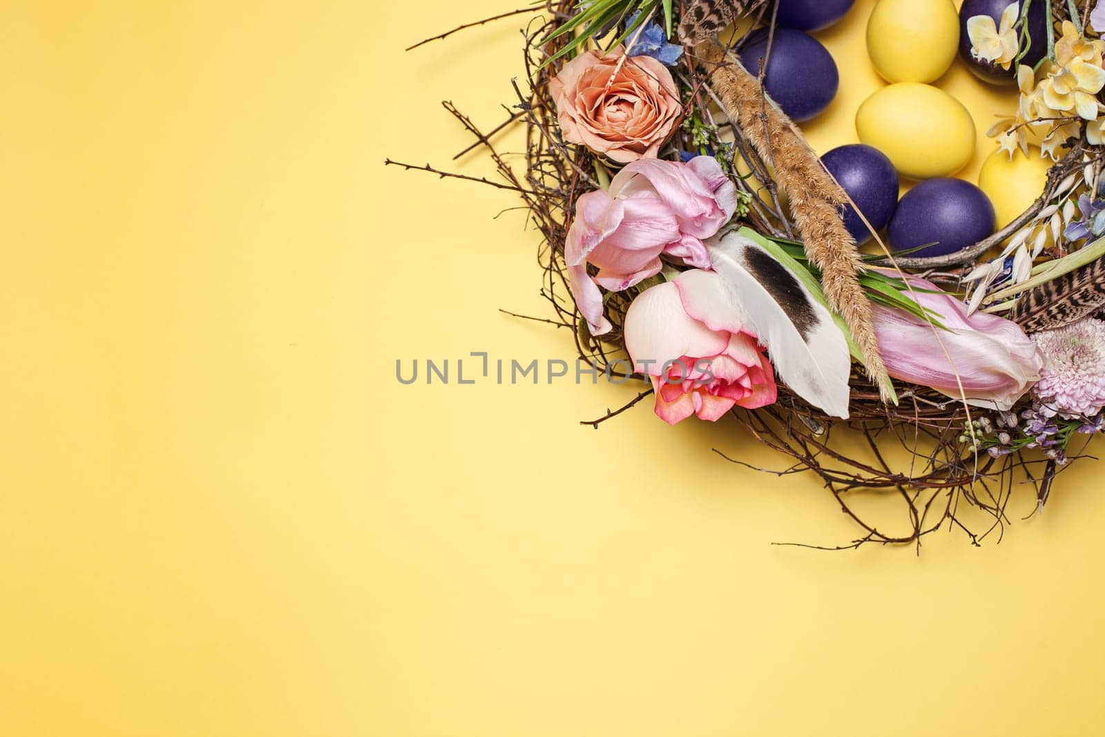 Easter card. Painted Easter eggs in nest on yellow table background. Top view of easter decoration. Happy easter concept. Trendy colors