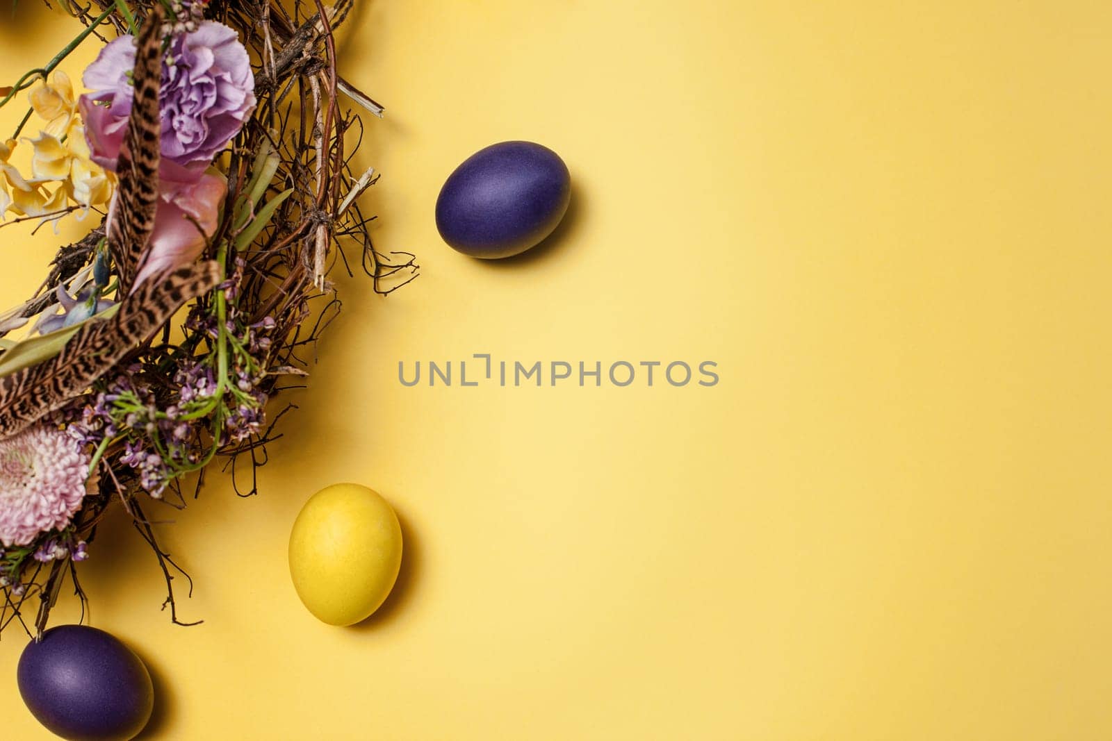 Easter card. Painted Easter eggs in nest on yellow table background. Top view of easter decoration. Happy easter concept. Trendy colors