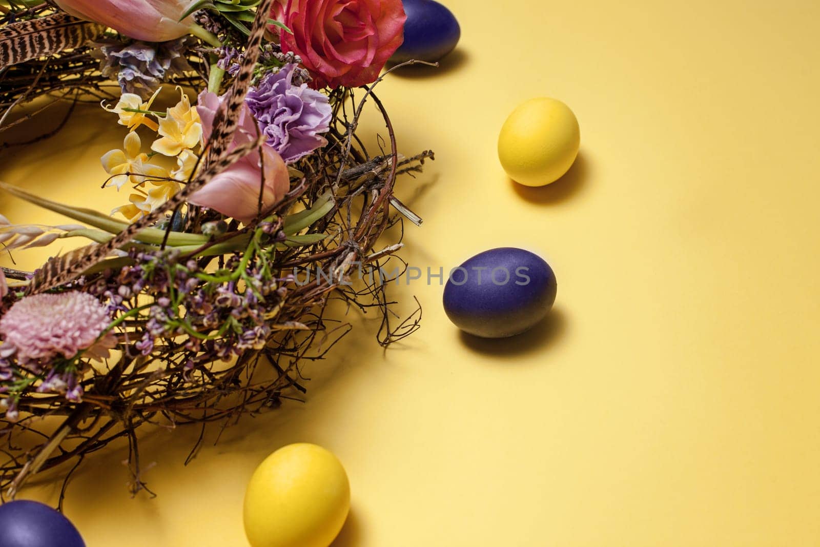 Easter card. Painted Easter eggs in nest on yellow table background. Top view of easter decoration. Happy easter concept. Trendy colors
