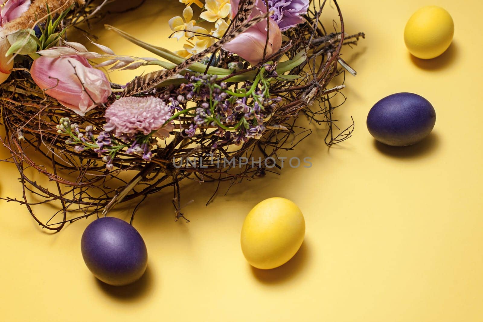 Easter card. Painted Easter eggs in nest on yellow table background. Top view of easter decoration. Happy easter concept. Trendy colors