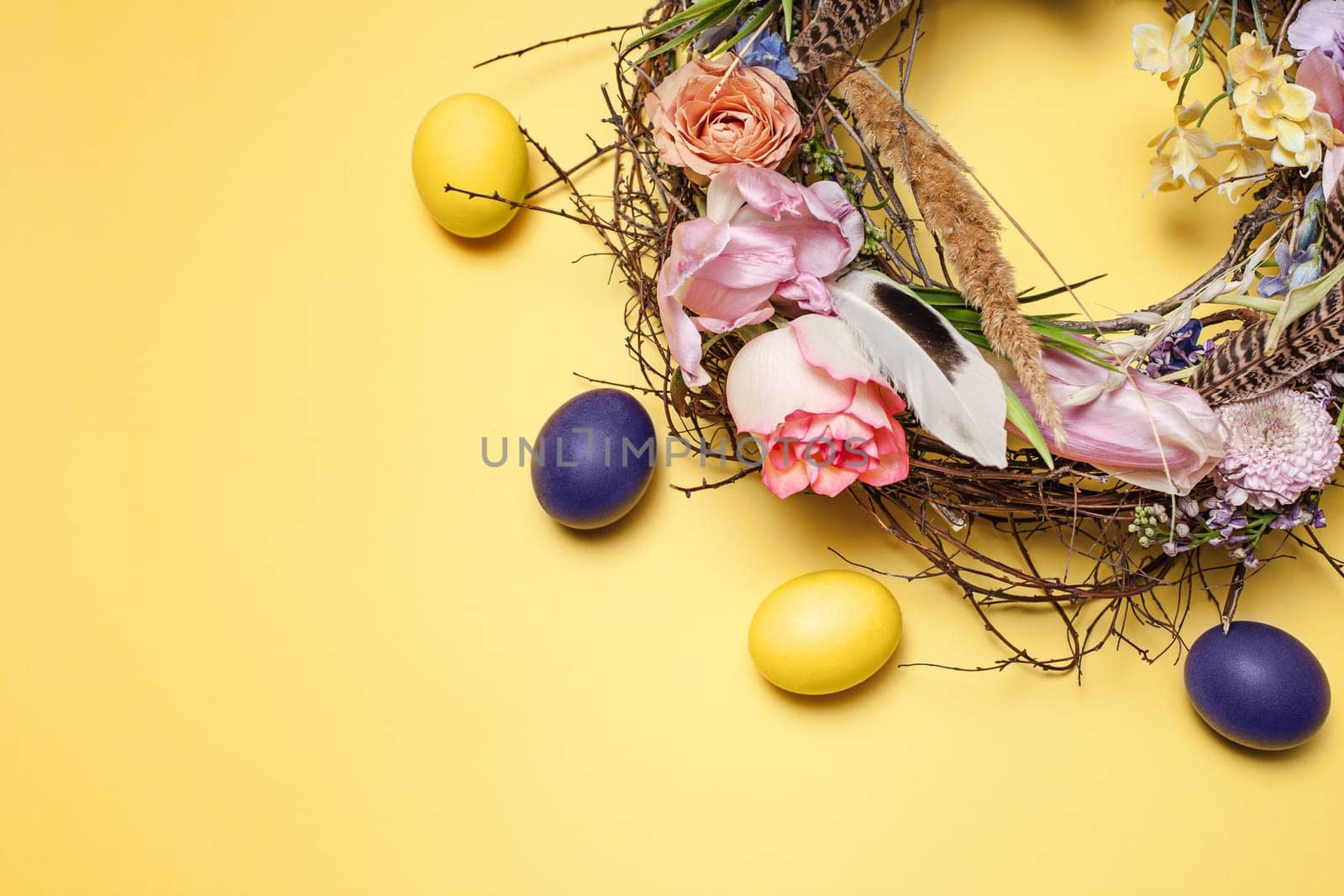 Easter card. Painted Easter eggs in nest on yellow table background. Top view of easter decoration. Happy easter concept. Trendy colors