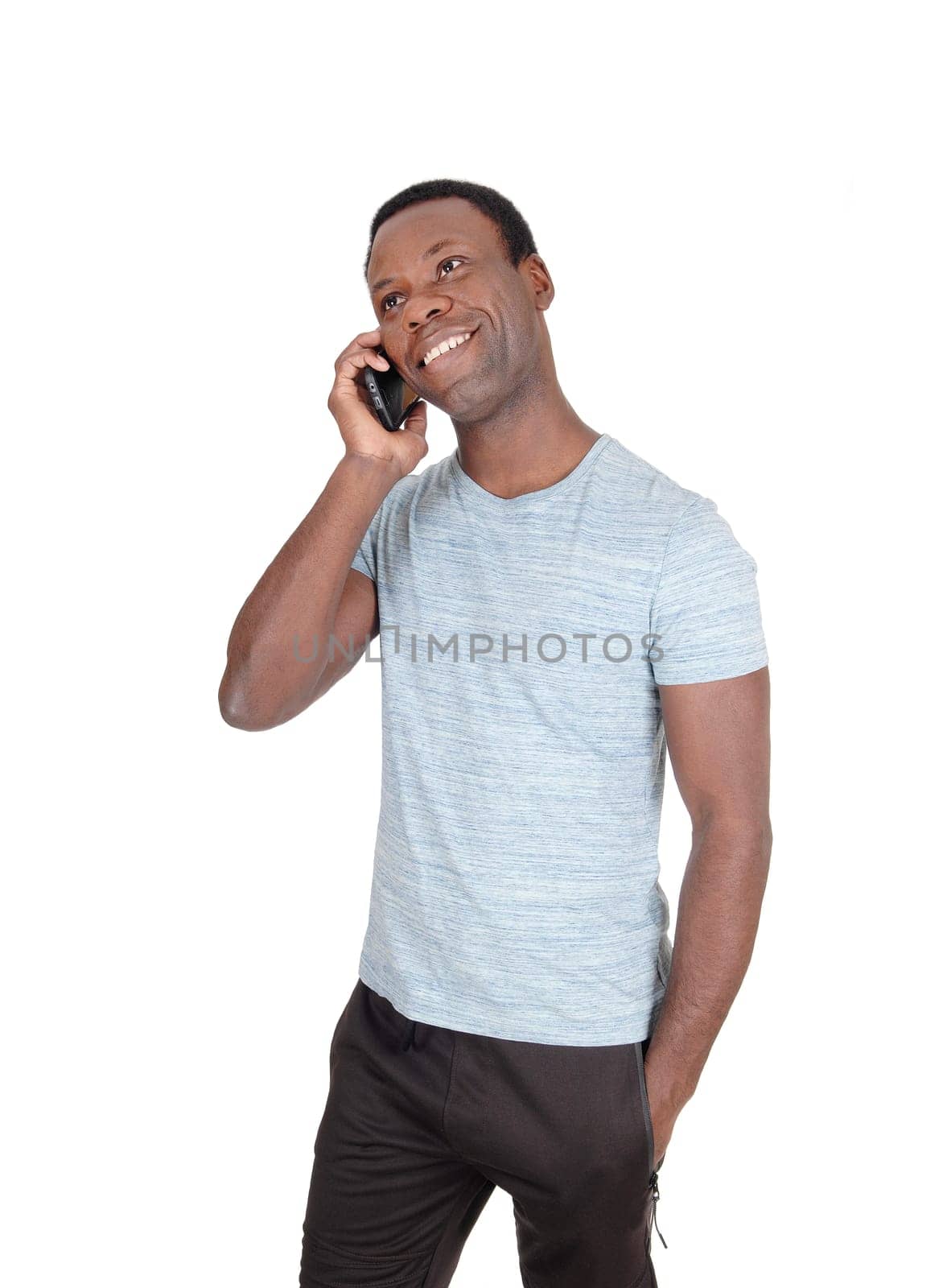 An handsome African American man standing in a gray t-shirt .talking at his cell phone and smiles, isolated for white background.