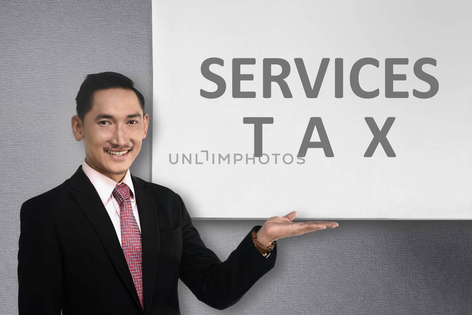 Young asian businessman standing beside whiteboard with service tax message. Goods and services tax concept