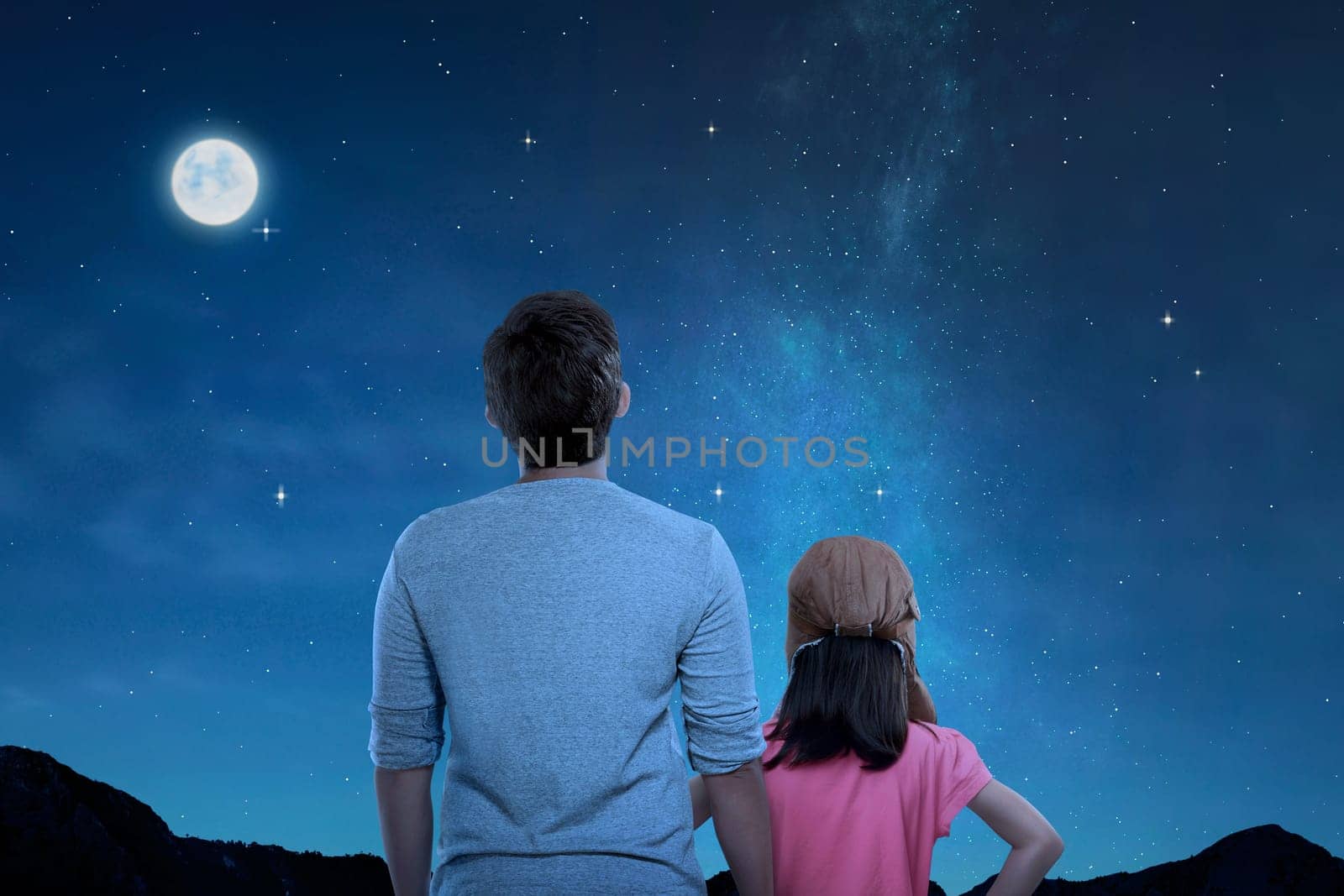 Rear view of father and little daughter looking at night scene at outdoor