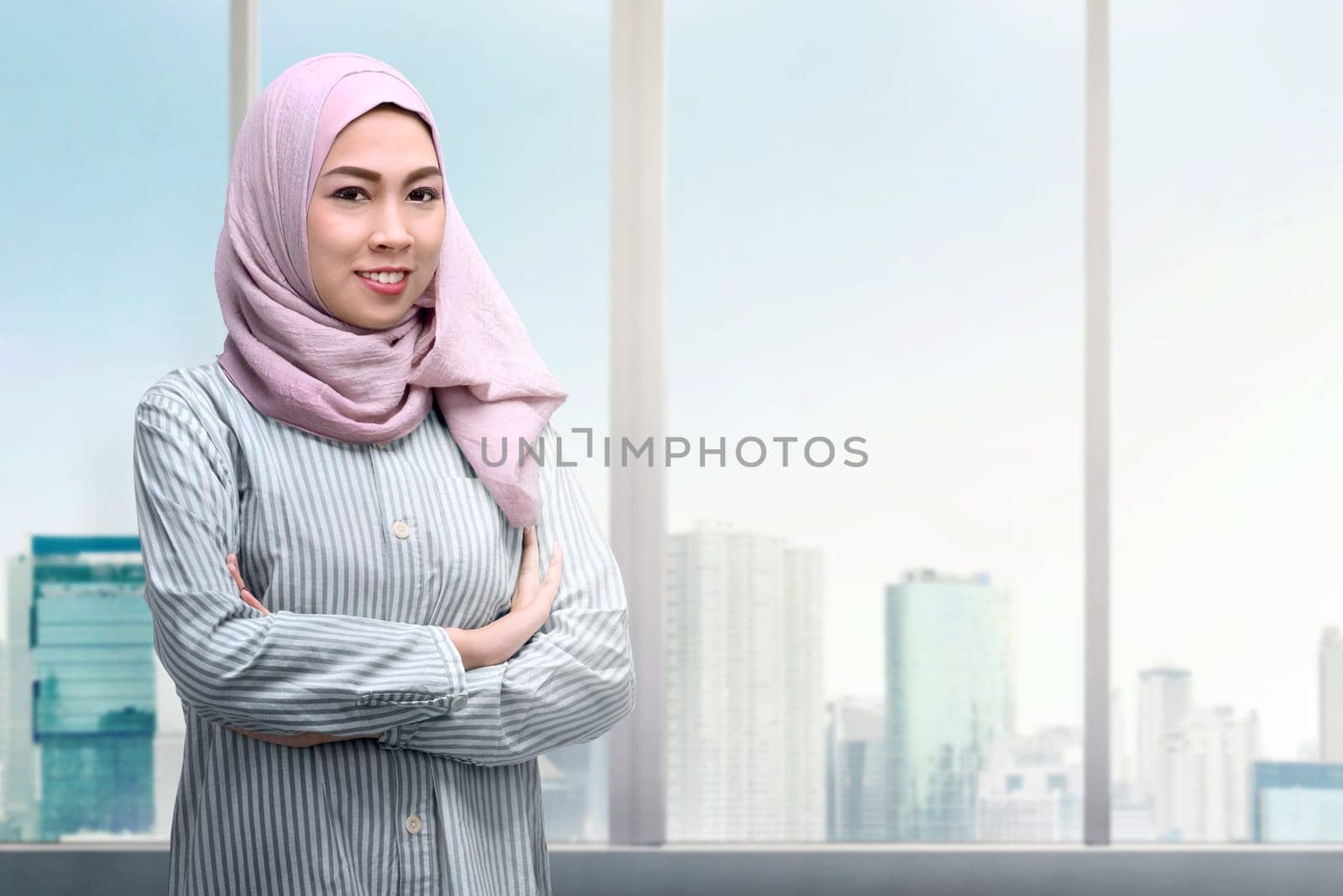 Pretty asian muslim woman with arms crossed standing with skyscrapers background