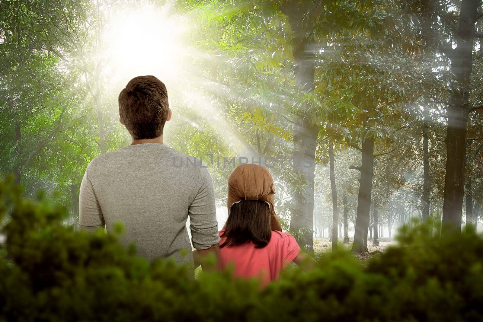 Back view of daughter and father relaxing together on the park