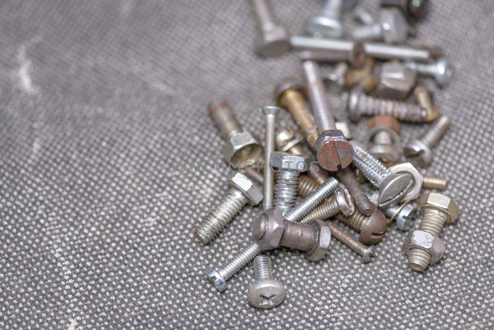 Several old screws on a grey texile background