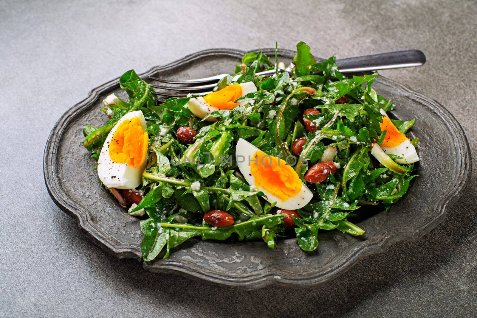 Fresh healthy dandelion salad with eggs and beans close up