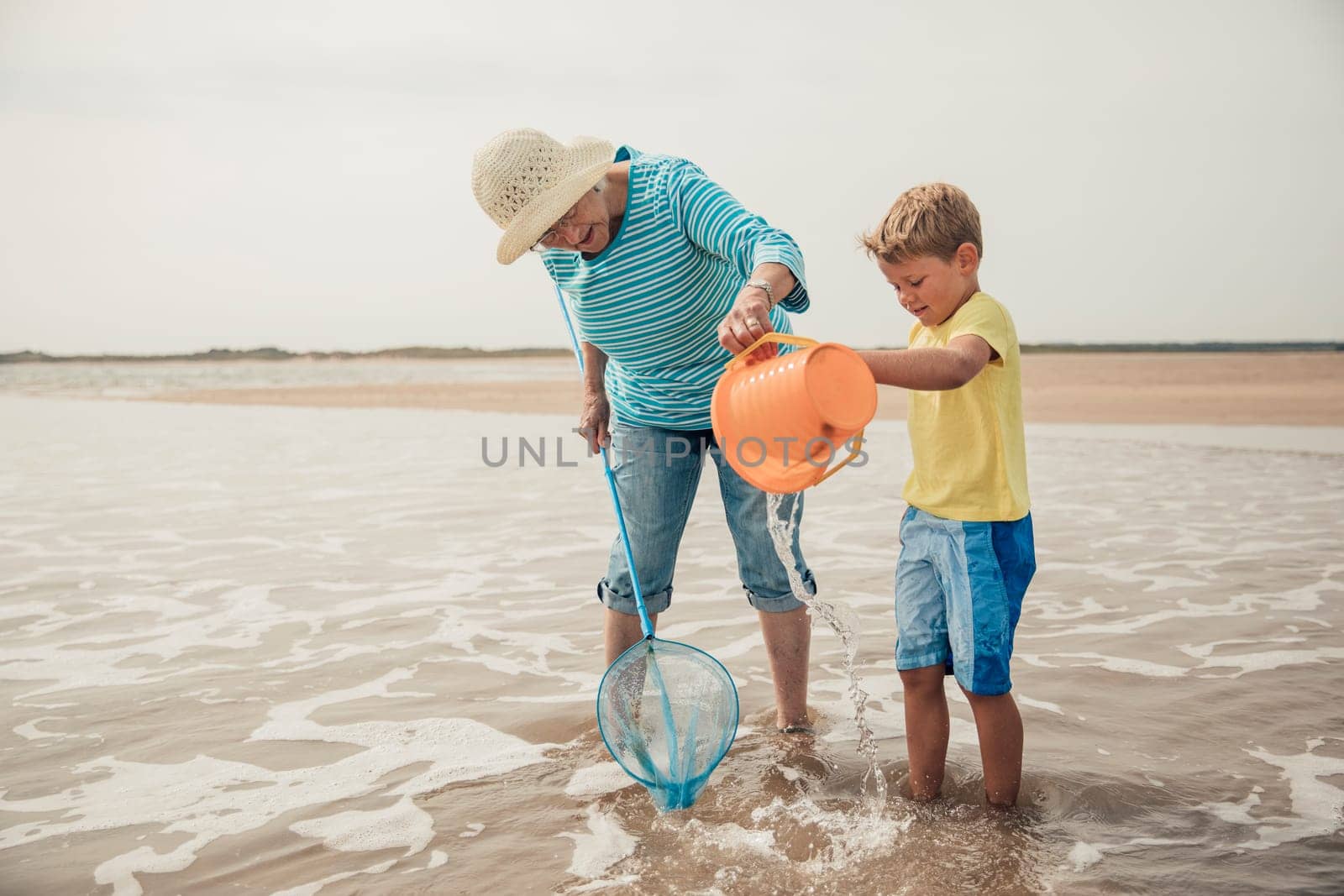Searching for sea artifacts with a bucket and fishing rod at the beach with grandma.