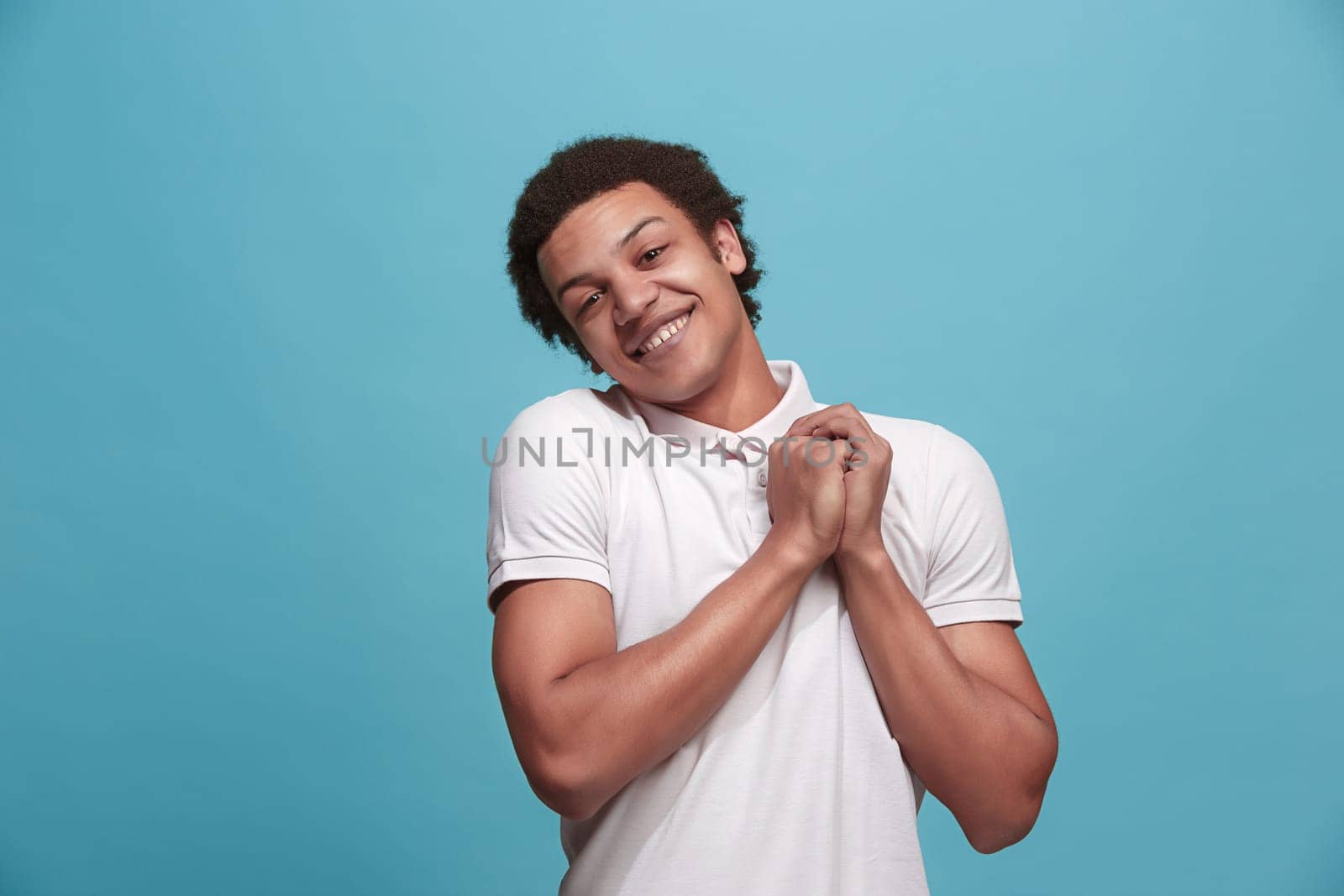 Delight. Beautiful male half-length front portrait isolated on blue studio backgroud. Young, emotional, smiling, surprised man standing. Human emotions, facial expression concept. Trendy colors