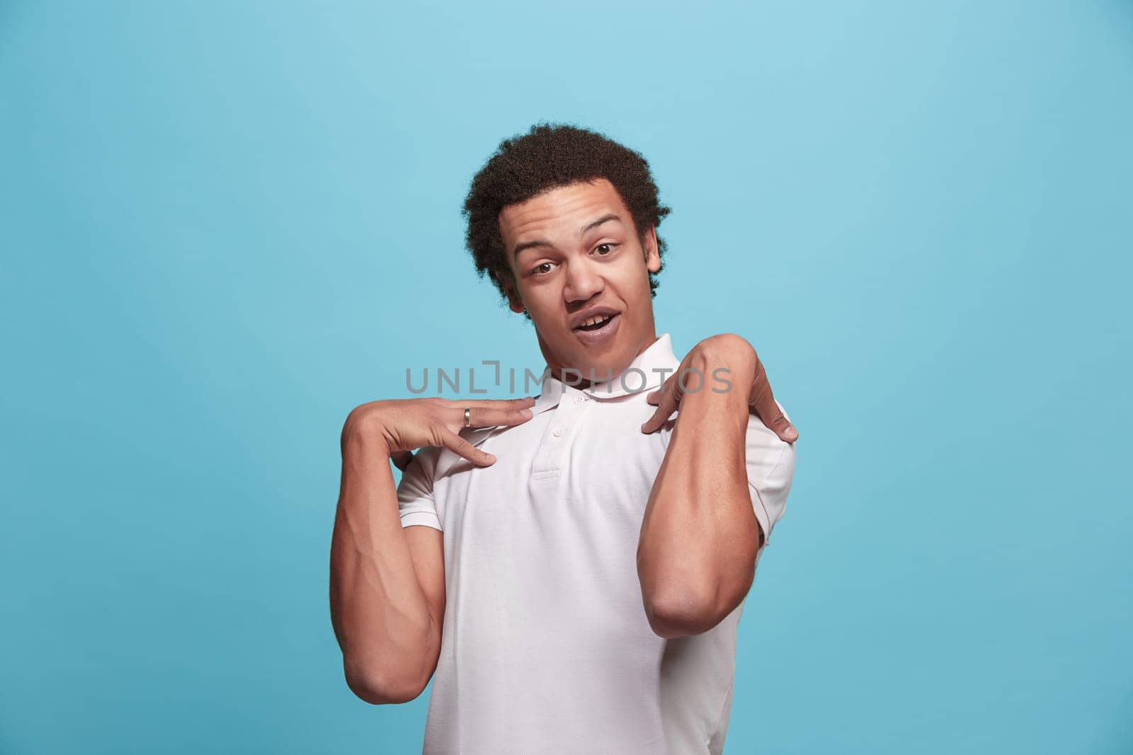 Argue, arguing concept. Beautiful male half-length portrait isolated on blue studio backgroud. Young emotional surprised man looking at camera. Human emotions, facial expression concept. Front view