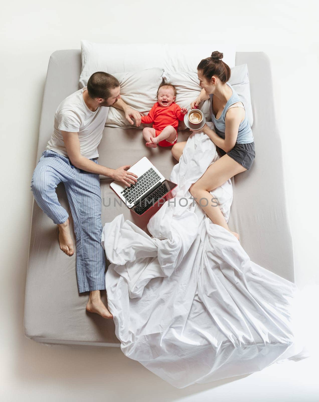 Top view of happy funny family with one newborn child in bedroom. Enjoying being together. Happy family in bed. Top view. Emotions concept. Morning after sleep. Family lifestyle. happy parents concept
