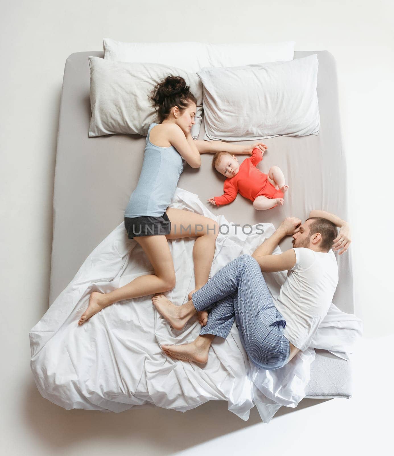 Top view of happy funny family with one newborn child in bedroom. Enjoying being together. Happy family in bed. Top view. Emotions concept. Morning after sleep. Family lifestyle. happy parents concept