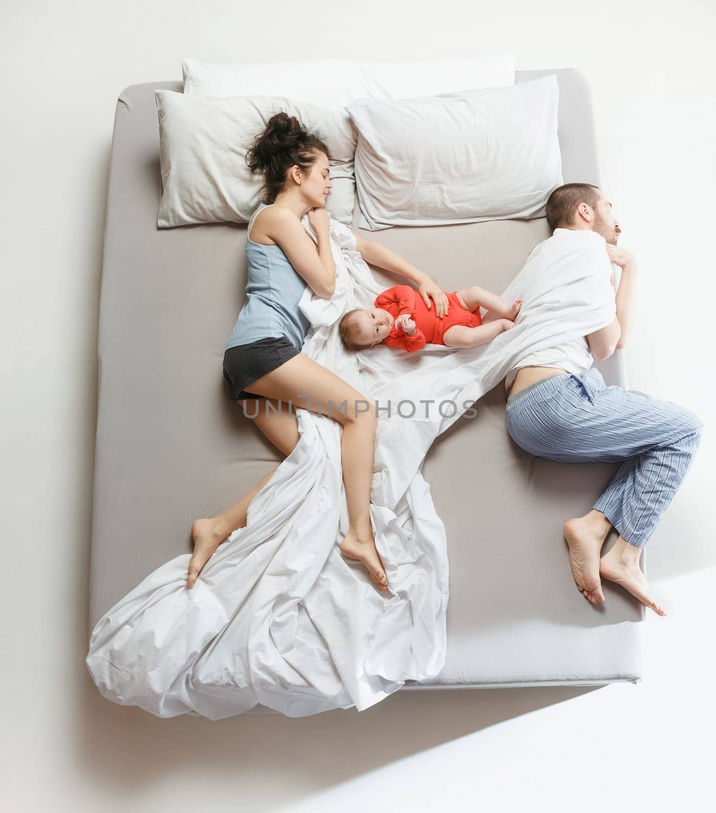 Top view of happy funny family with one newborn child in bedroom. Enjoying being together. Happy family in bed. Top view. Emotions concept. Morning after sleep. Family lifestyle. happy parents concept
