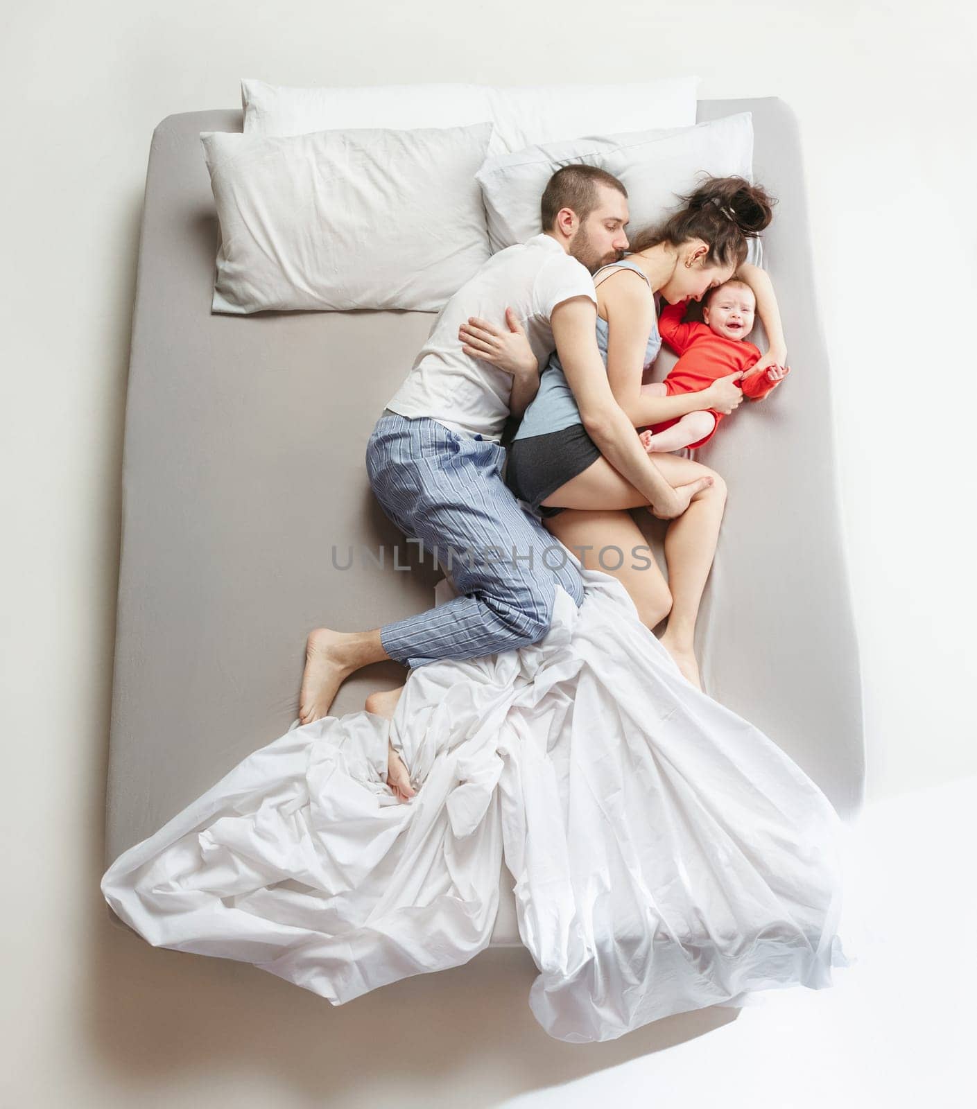 Top view of happy funny family with one newborn child in bedroom. Enjoying being together. Happy family in bed. Top view. Emotions concept. Morning after sleep. Family lifestyle. happy parents concept