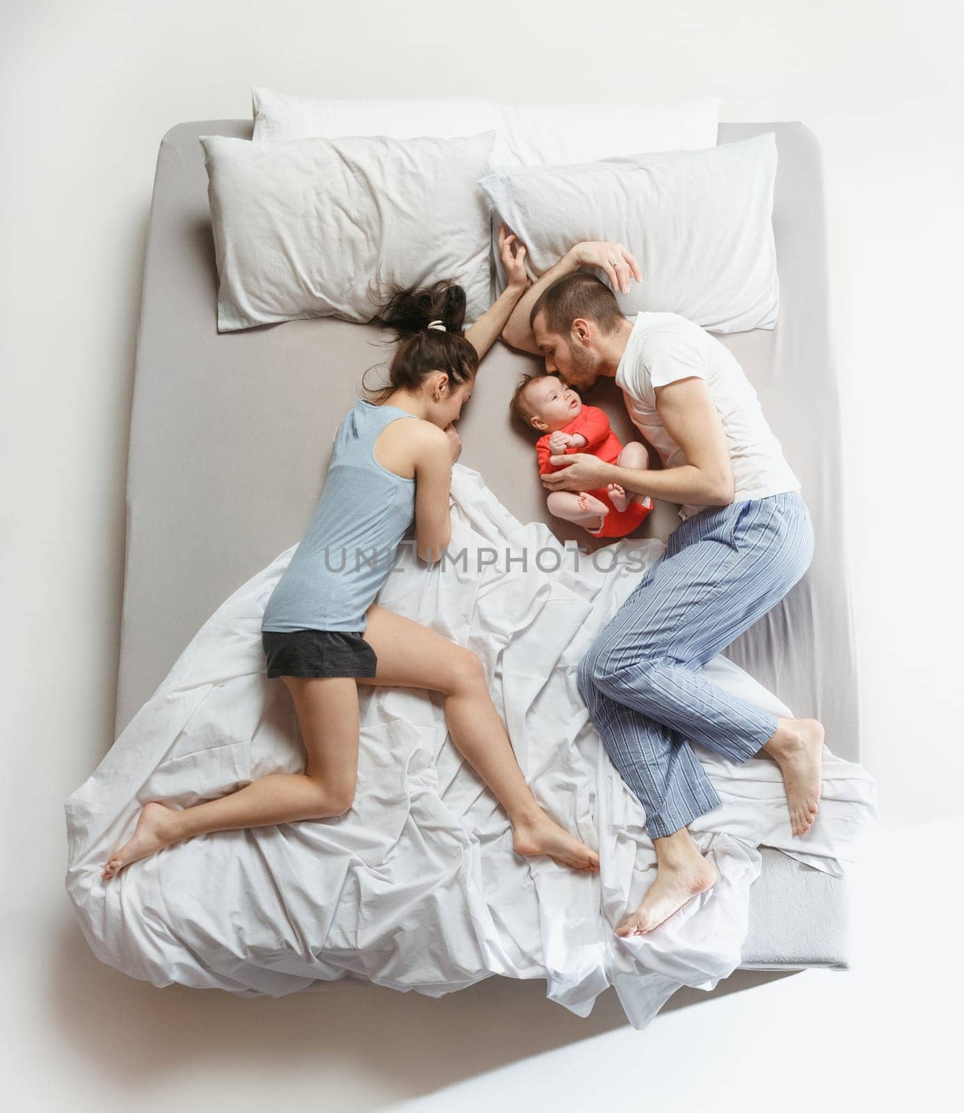 Top view of happy funny family with one newborn child in bedroom. Enjoying being together. Happy family in bed. Top view. Emotions concept. Morning after sleep. Family lifestyle. happy parents concept