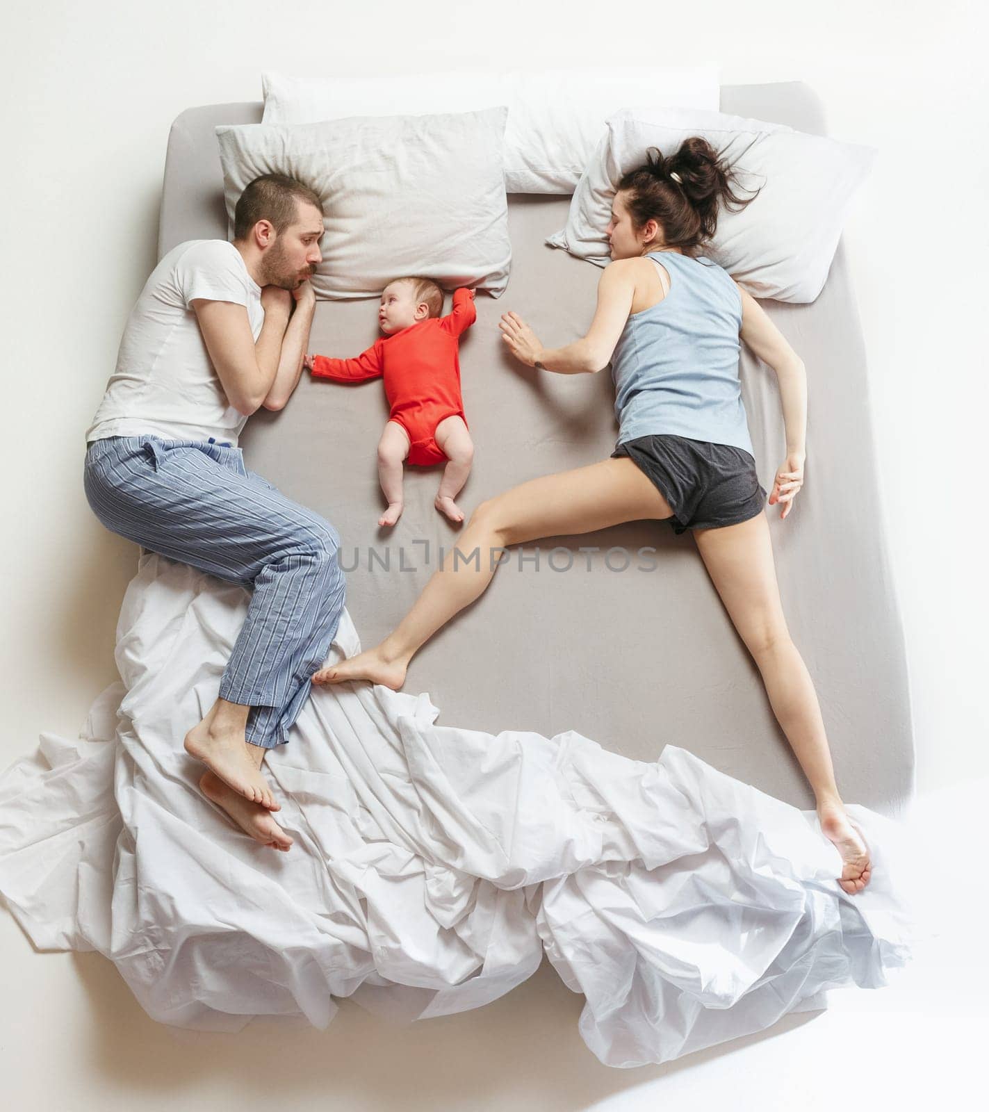 Top view of happy funny family with one newborn child in bedroom. Enjoying being together. Happy family in bed. Top view. Emotions concept. Morning after sleep. Family lifestyle. happy parents concept