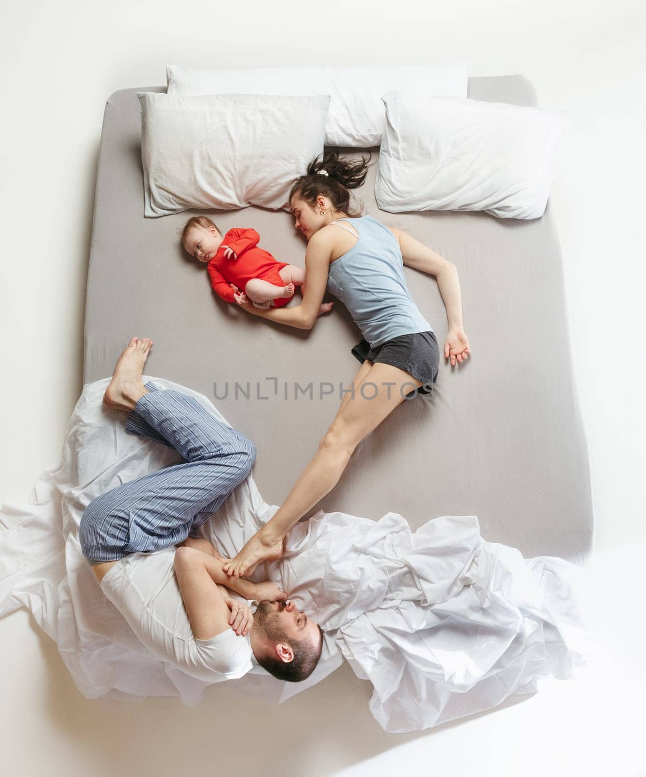 Top view of happy funny family with one newborn child in bedroom. Enjoying being together. Happy family in bed. Top view. Emotions concept. Morning after sleep. Family lifestyle. happy parents concept