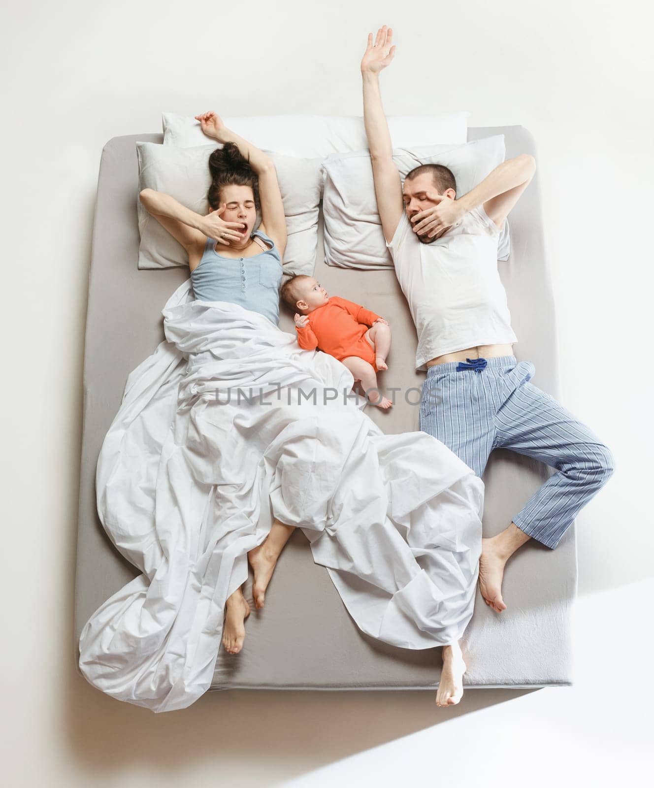 Top view of happy funny family with one newborn child in bedroom. Enjoying being together. Happy family in bed. Top view. Emotions concept. Morning after sleep. Family lifestyle. happy parents concept