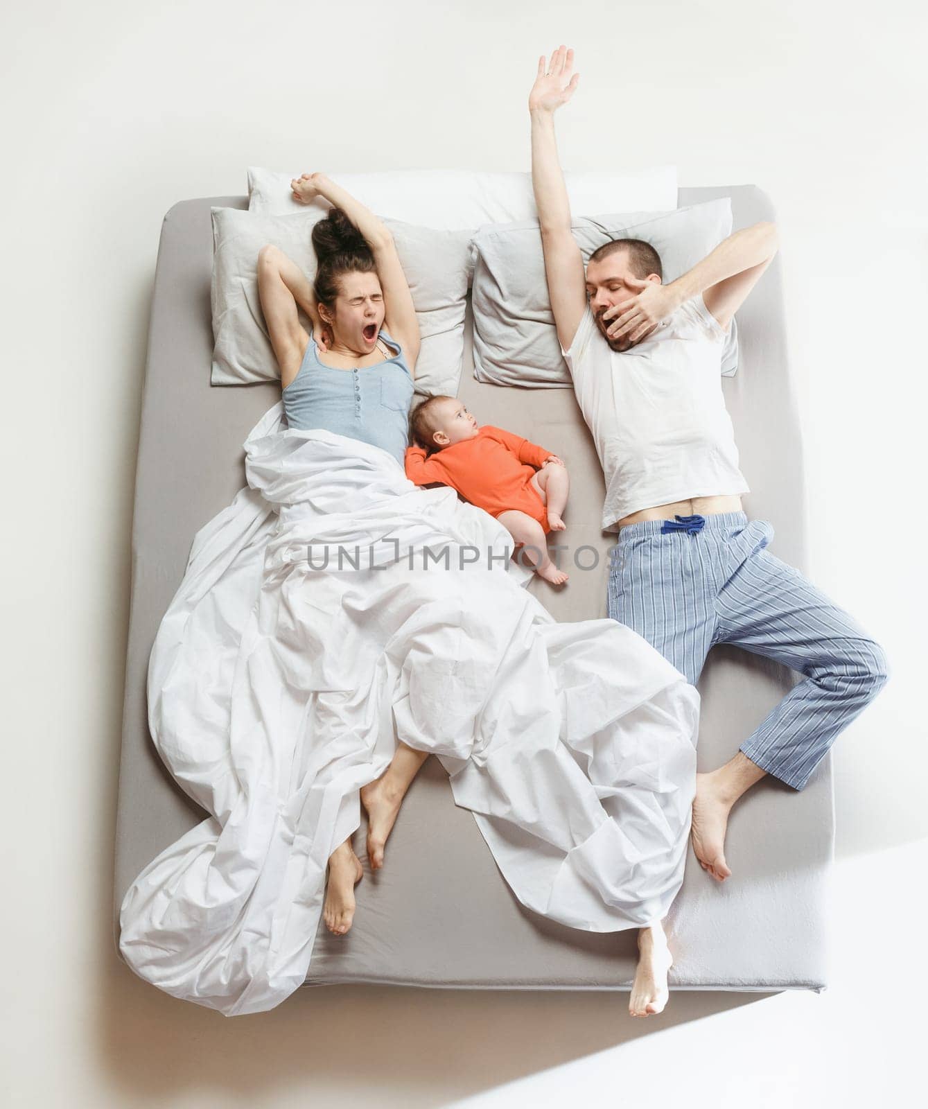Top view of happy funny family with one newborn child in bedroom. Enjoying being together. Happy family in bed. Top view. Emotions concept. Morning after sleep. Family lifestyle. happy parents concept