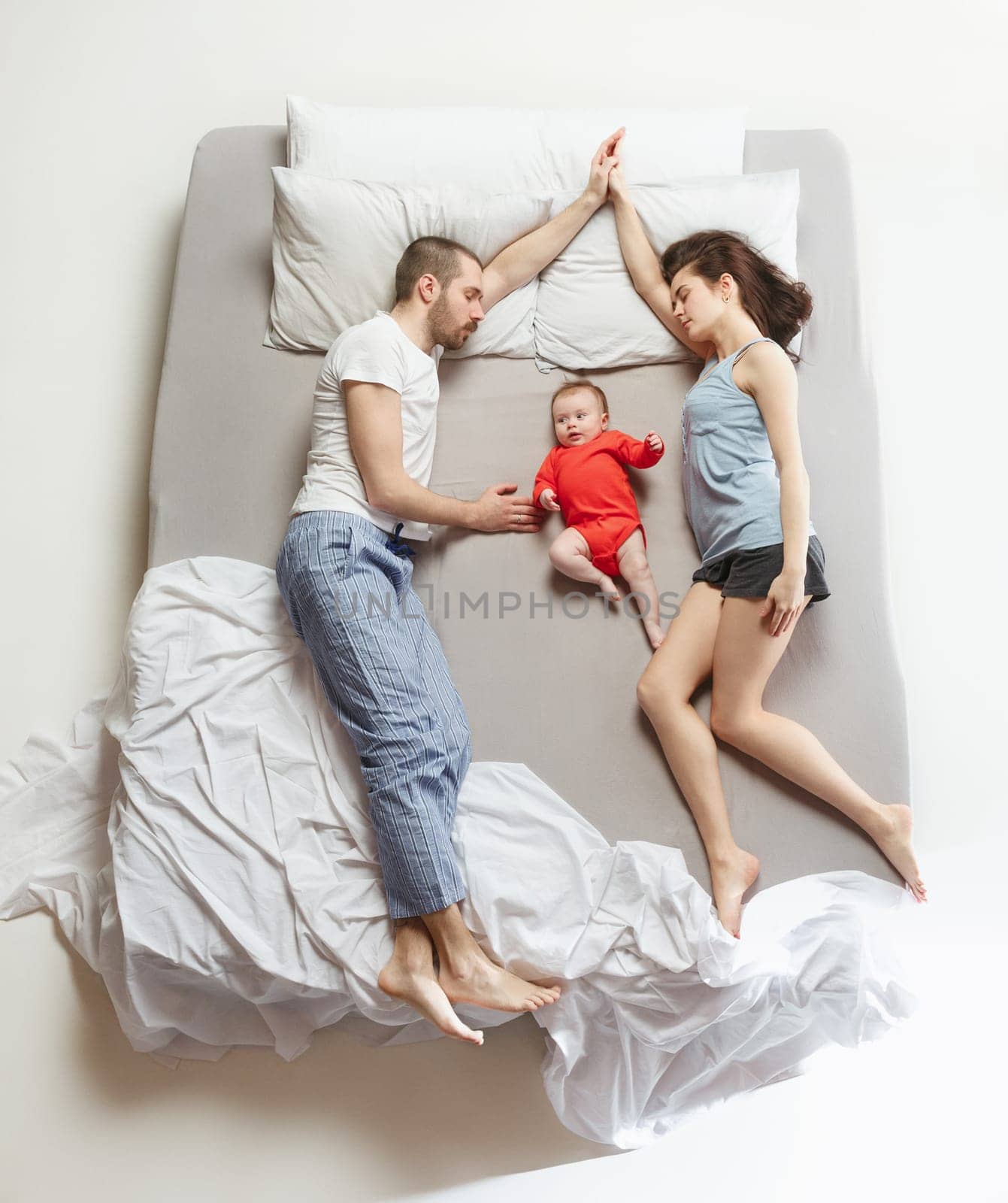 Top view of happy funny family with one newborn child in bedroom. Enjoying being together. Happy family in bed. Top view. Emotions concept. Morning after sleep. Family lifestyle. happy parents concept